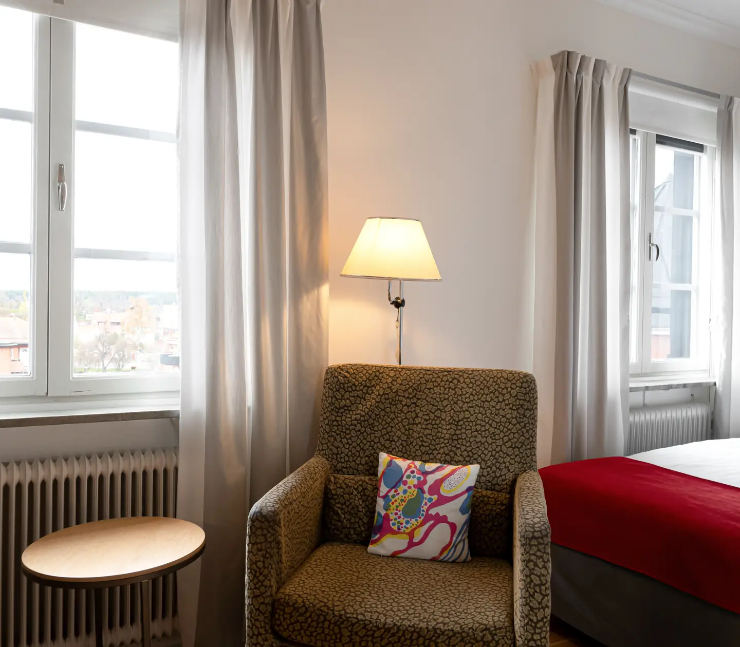 Ljust hotellrum med säng, fåtölj och fönster