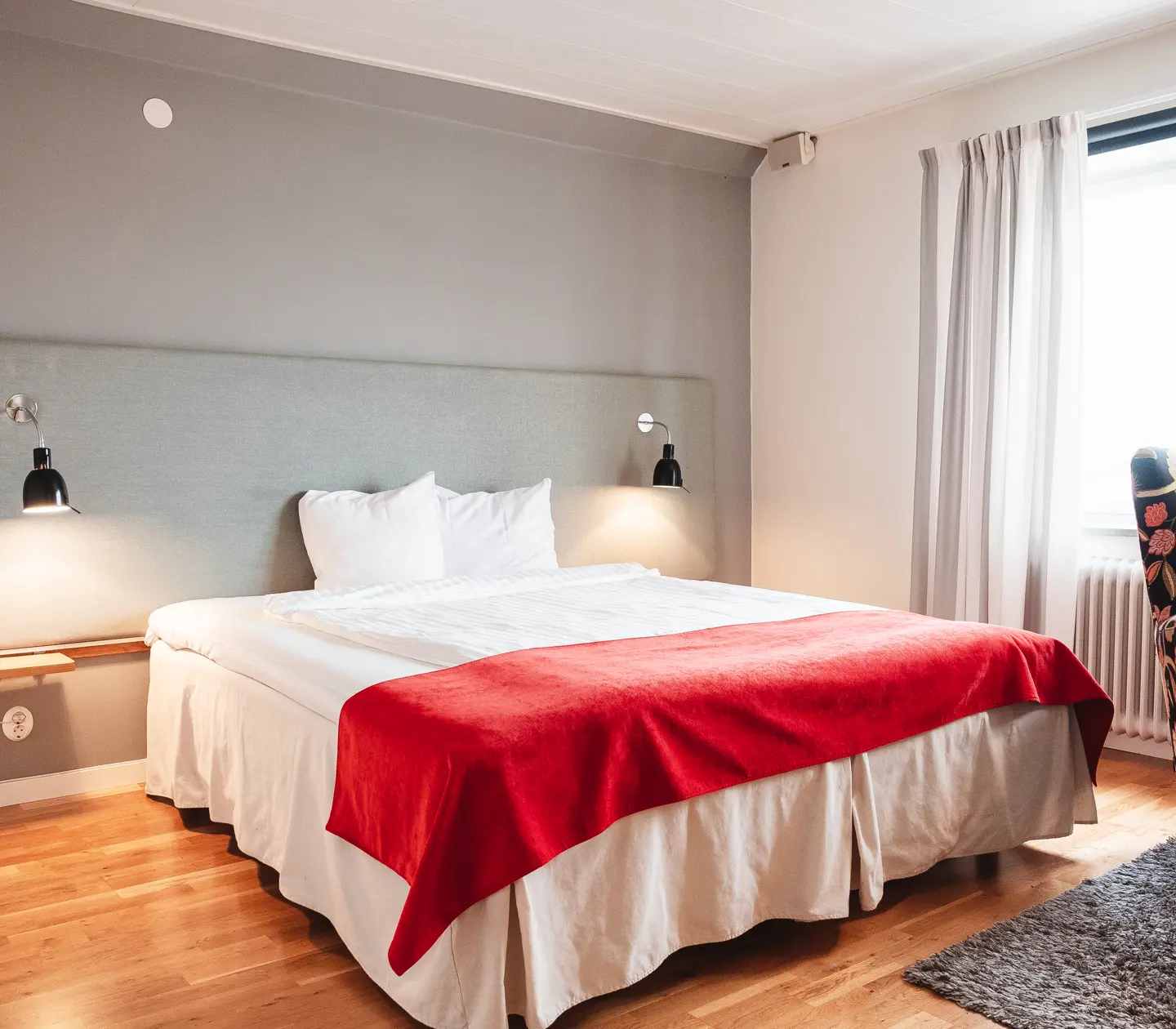 Mysigt hotellrum med säng, fåtölj och fönster