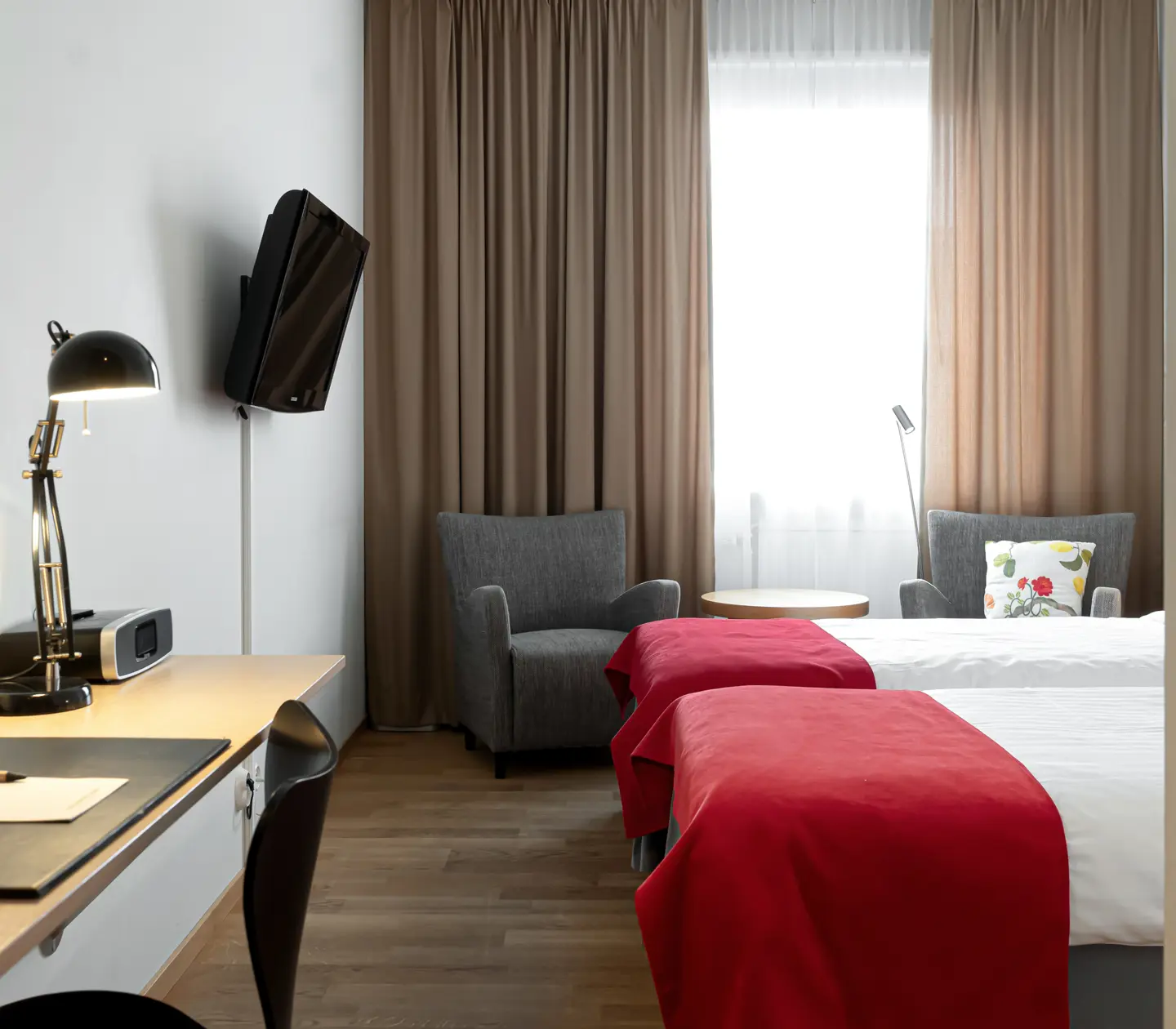 Mysigt hotellrum med sängar, fåtöljer och skrivbord