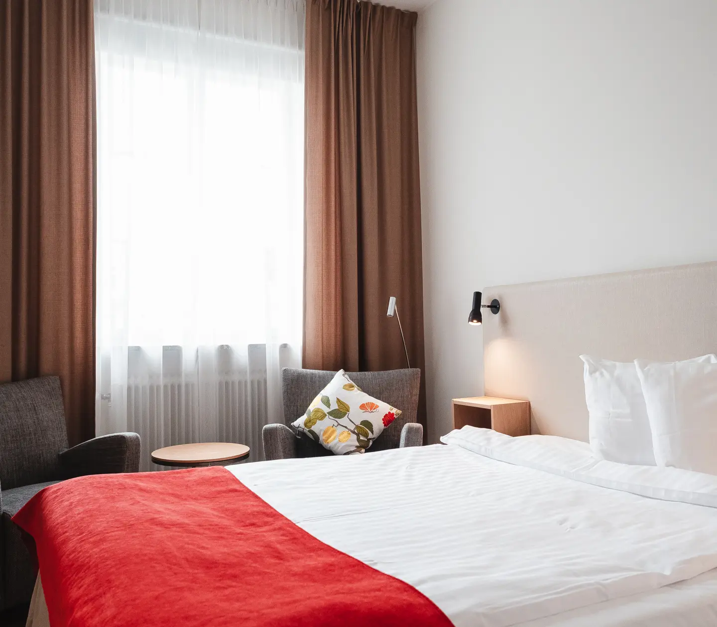 Mysigt hotellrum med säng, fåtölj och fönster