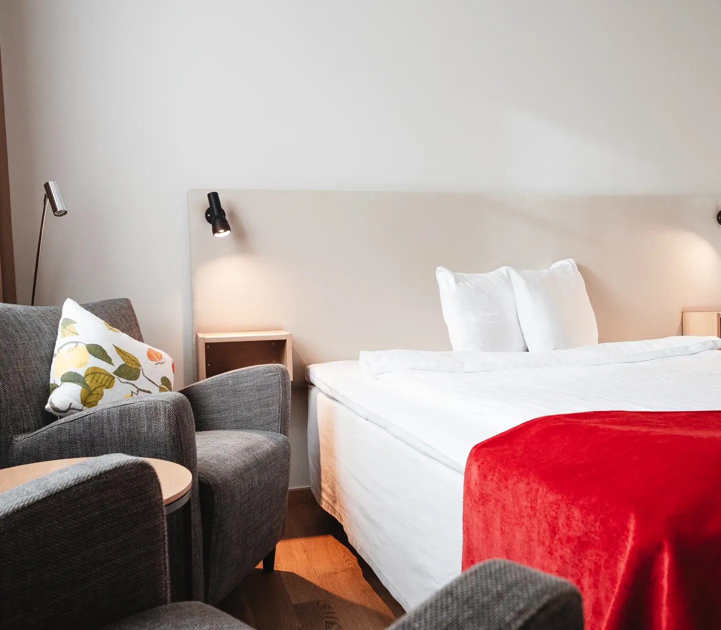 Mysigt hotellrum med säng, fåtöljer och sänglampor