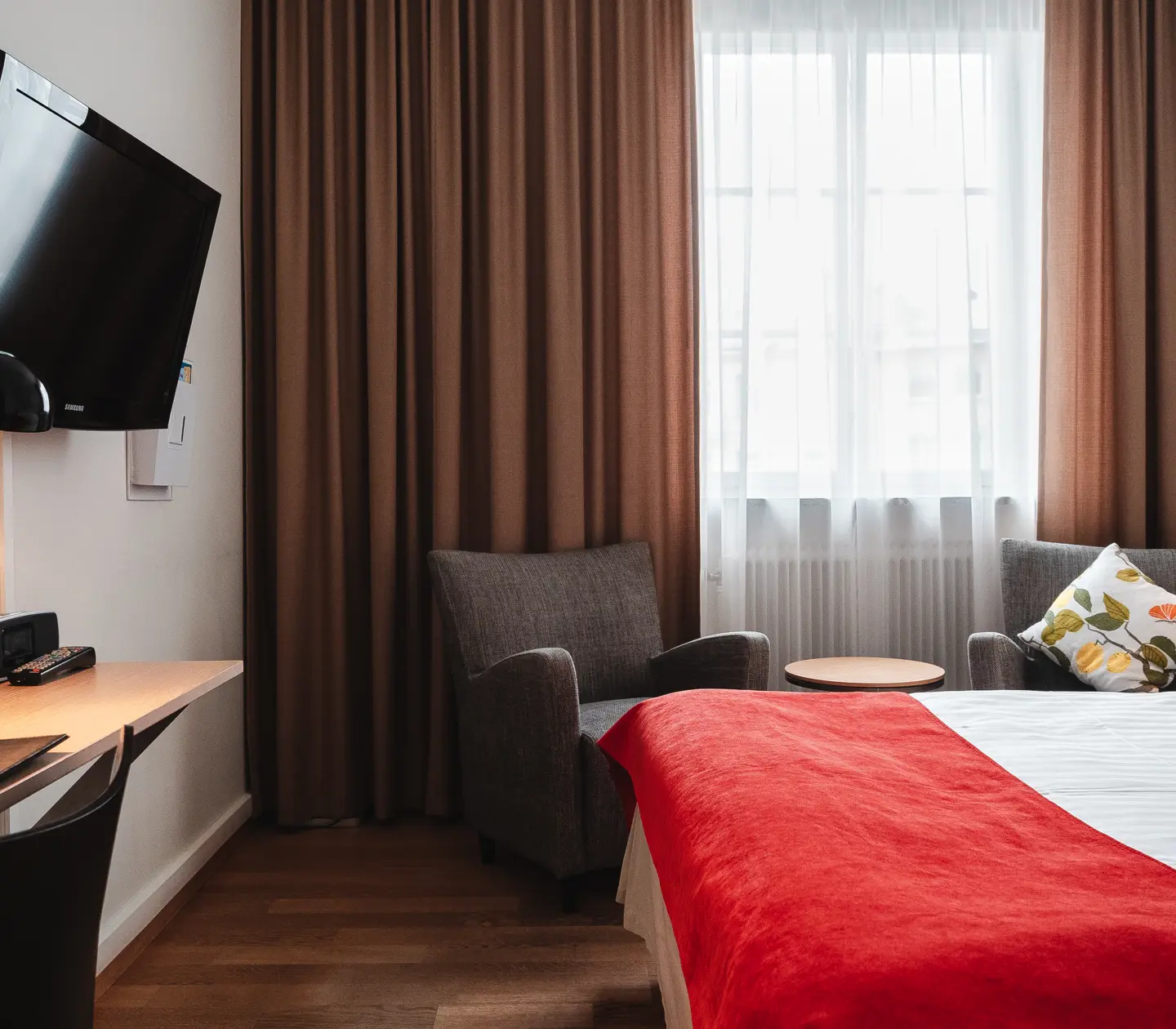 Mysigt hotellrum med säng, fåtöljer och tv