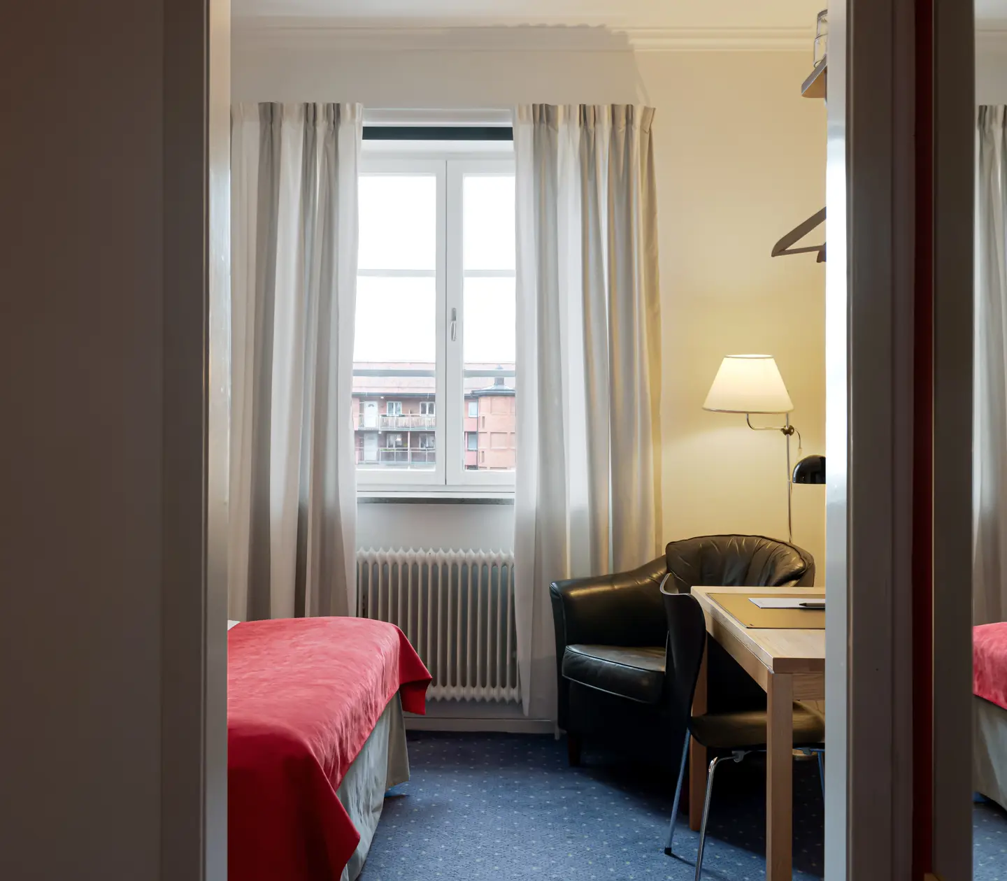 Hotellrum med skrivbord, fåtölj och fönster