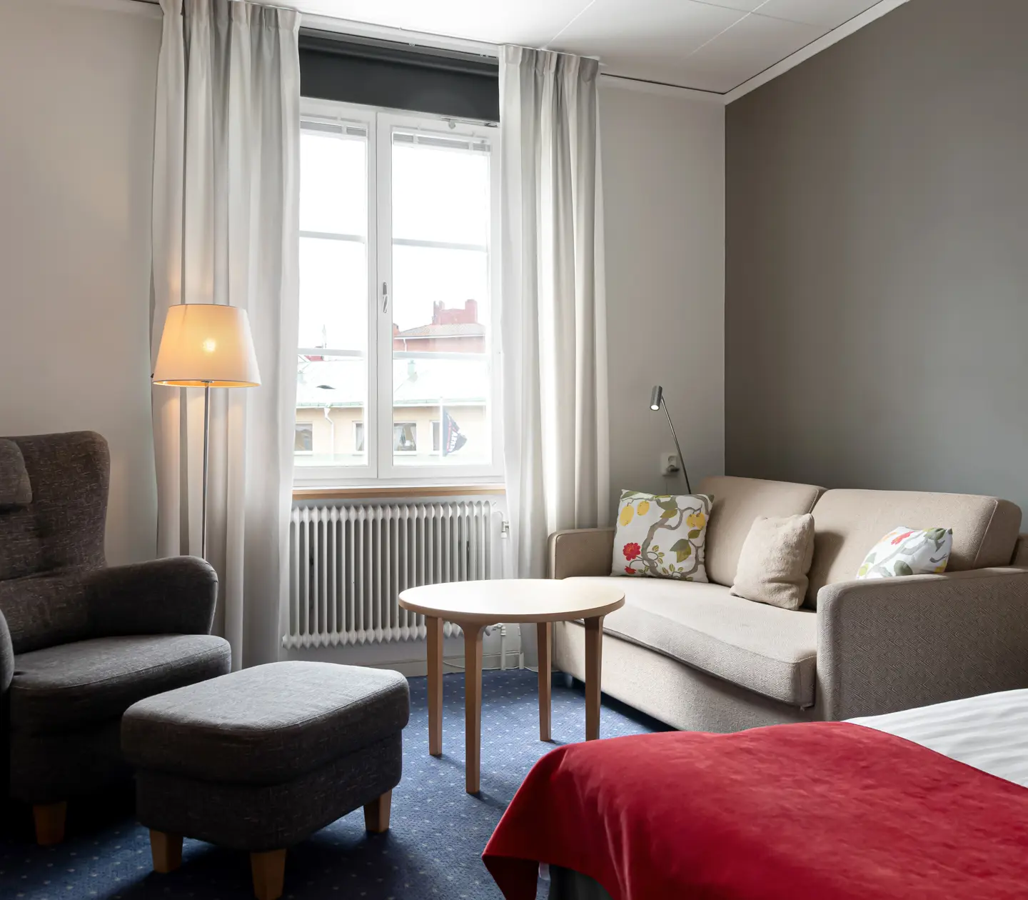 Mysigt hotellrum med säng, sittgrupp och fönster