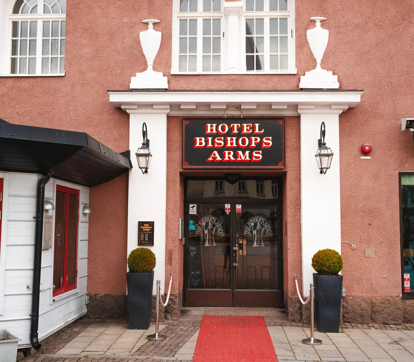 Entrén till Hotel Bishops Arms med röd matta och växter utanför