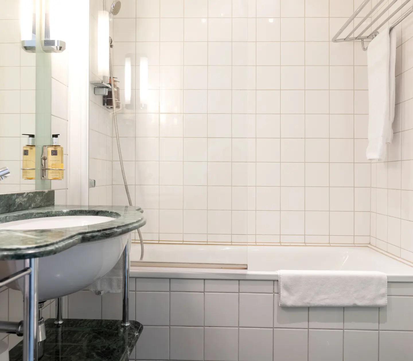 Ljust badrum med badkar, grönt handfat och handdukar