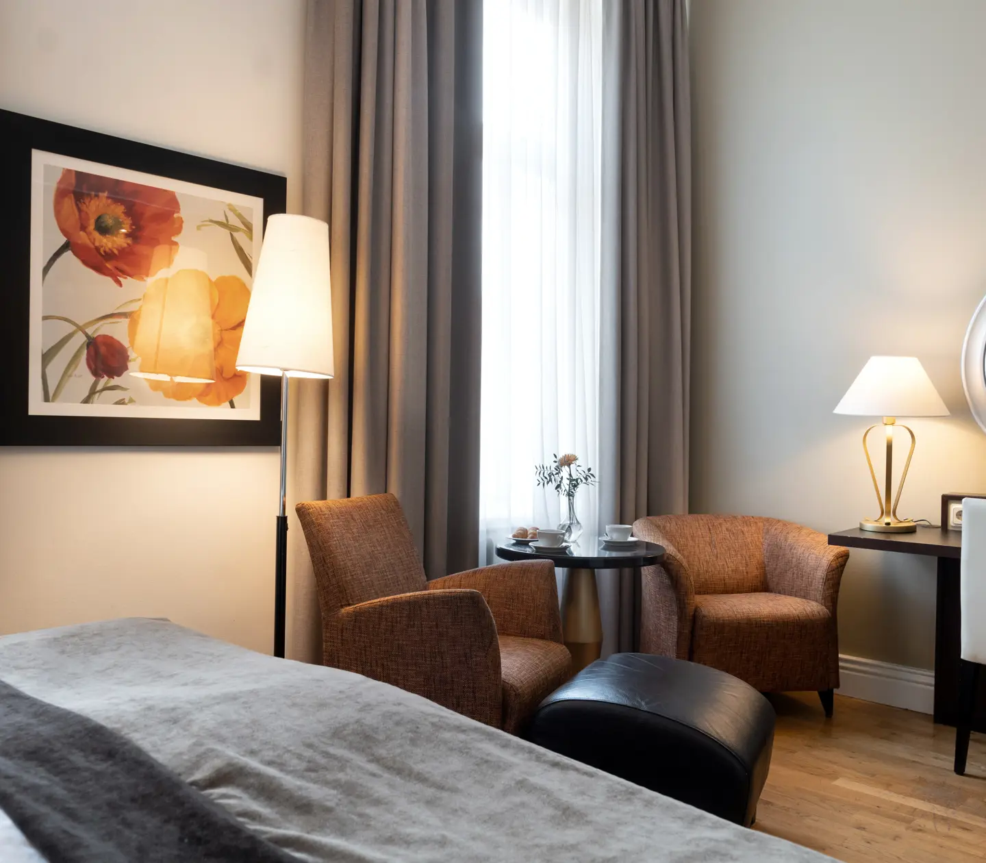 Ljust hotellrum med säng, skrivbord och fåtöljer