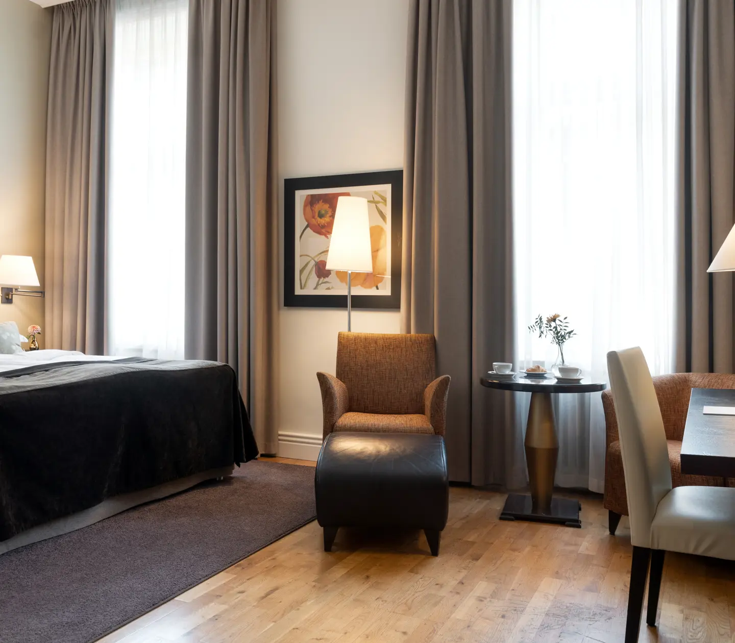 Ljust hotellrum med säng, skrivbord och stora fönster