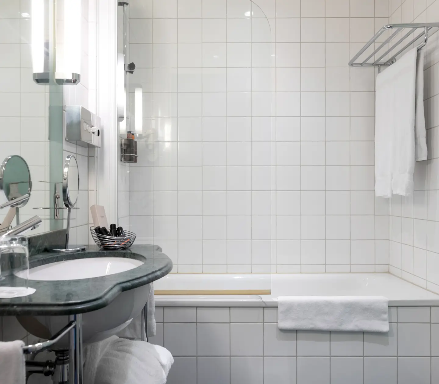 Ljust badrum med badkar, grönt handfat och handdukar