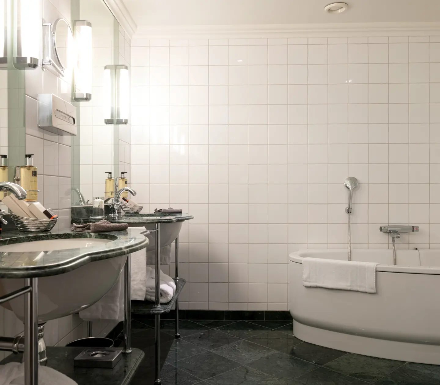 Ljust badrum med badkar, dubbla gröna handfat och handdukar