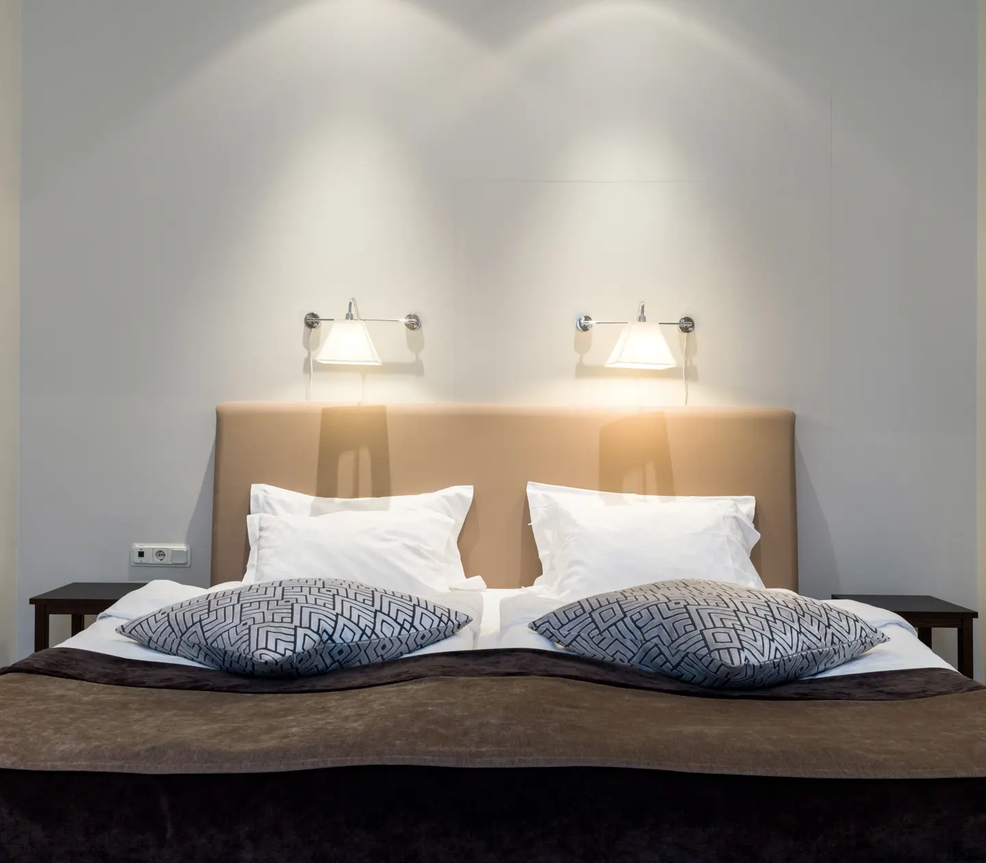 Ljus svit med säng, sänglampor och blåmönstrade kuddar