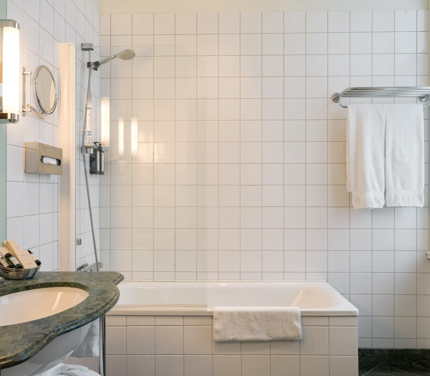 Ljust badrum med badkar, grönt handfat och handdukar
