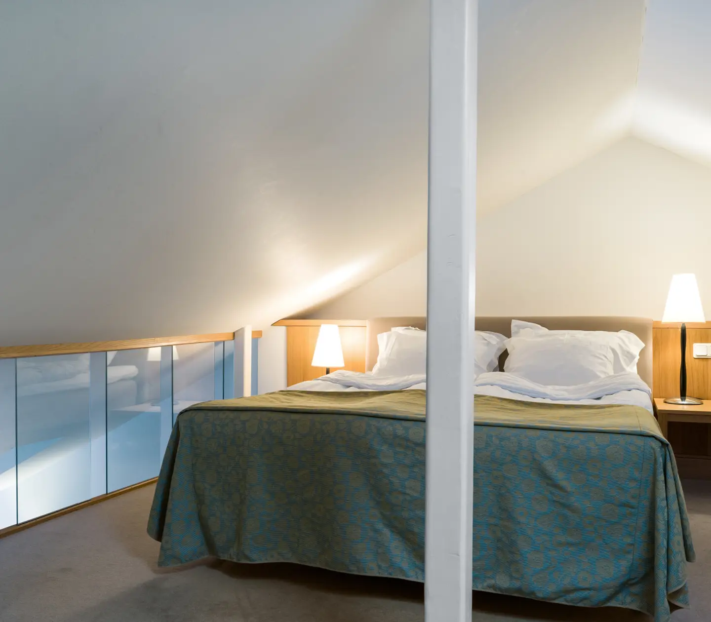Ljus svit med säng, sänglampor och glasräcke