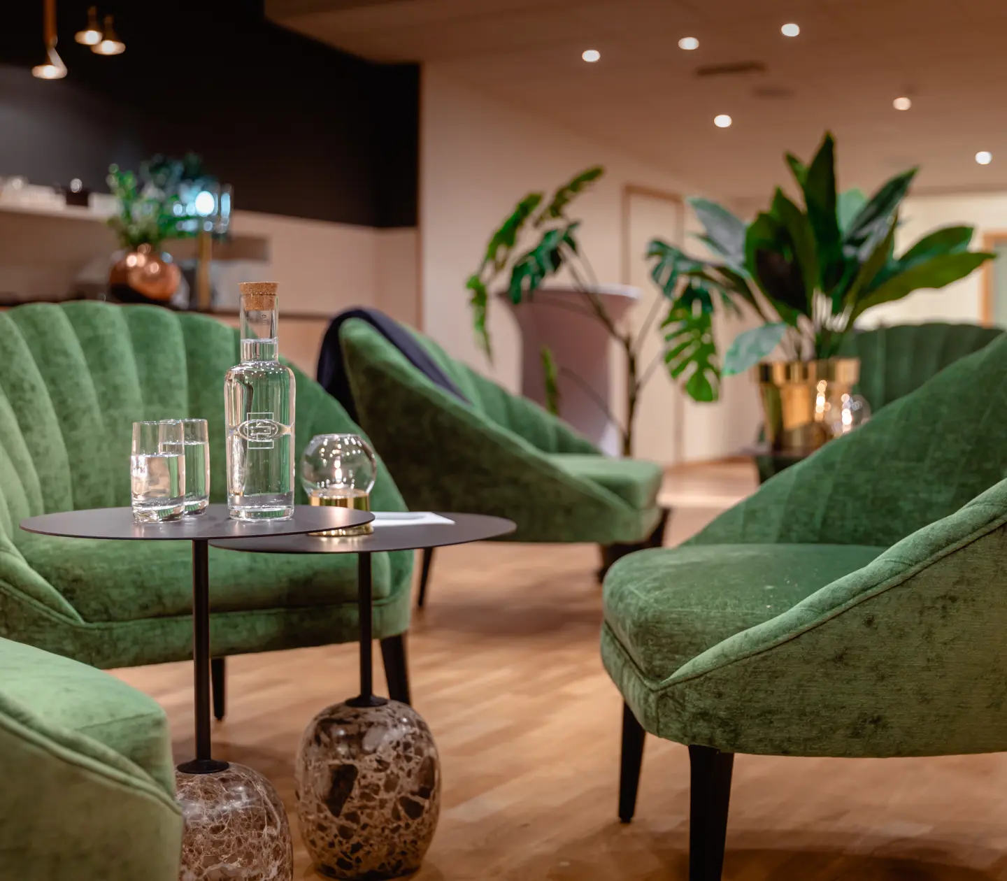 Konferensmiljö med gröna fåtöljer, vattenglas och växter