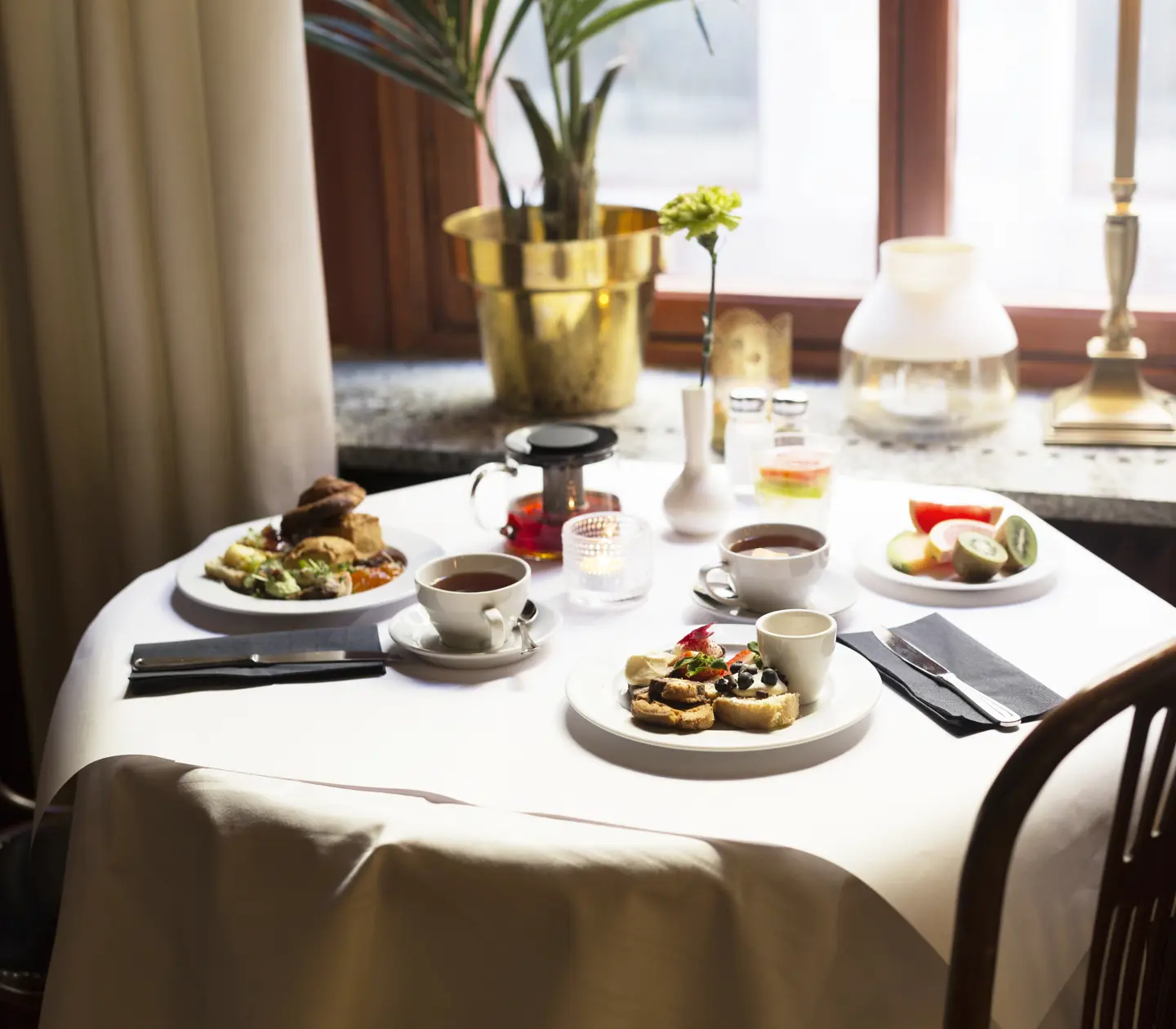Frukost serverad på runt bord framför fönster