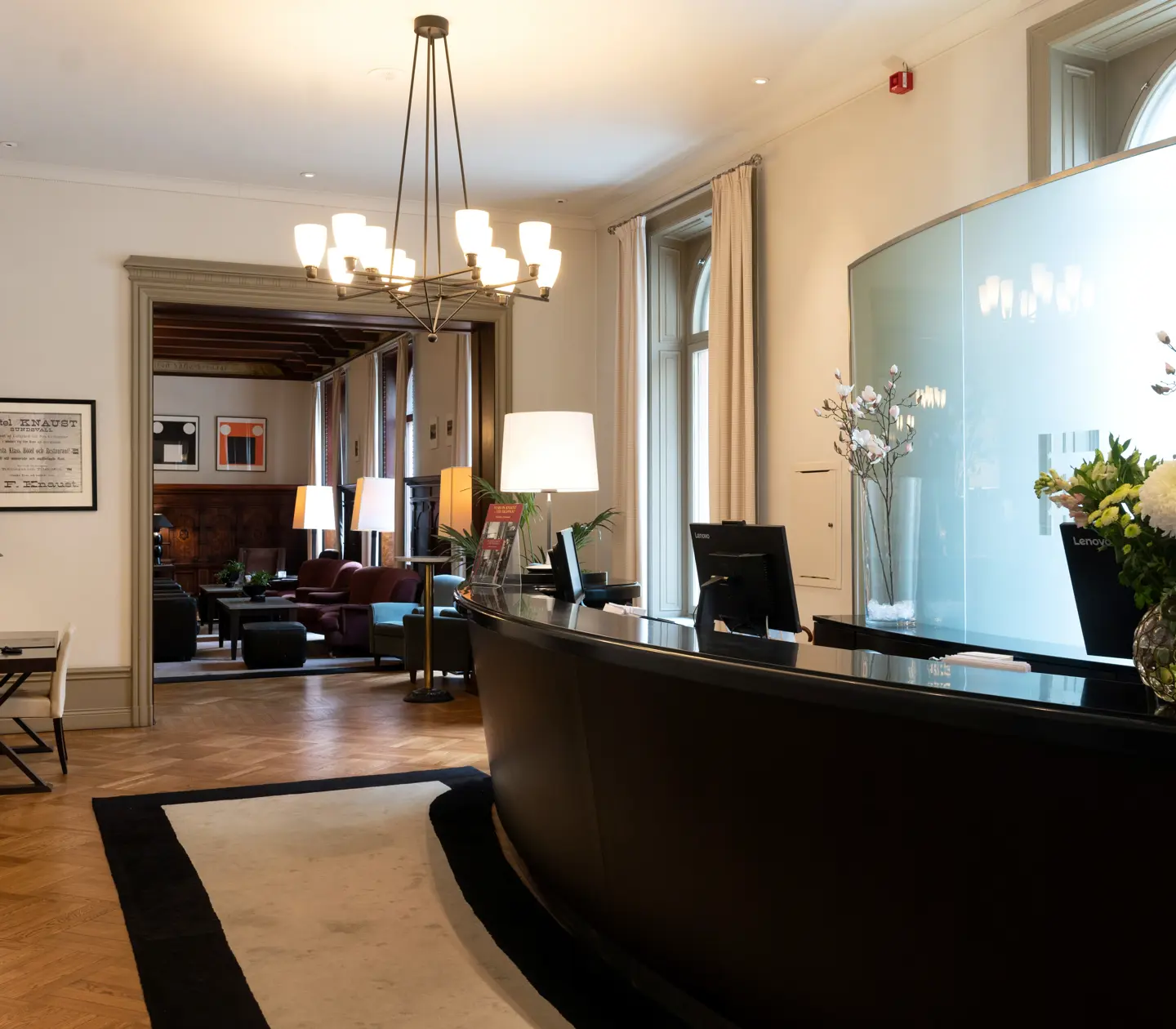 Hotellobby med receptionsdisk, loungemöbler och blombukett