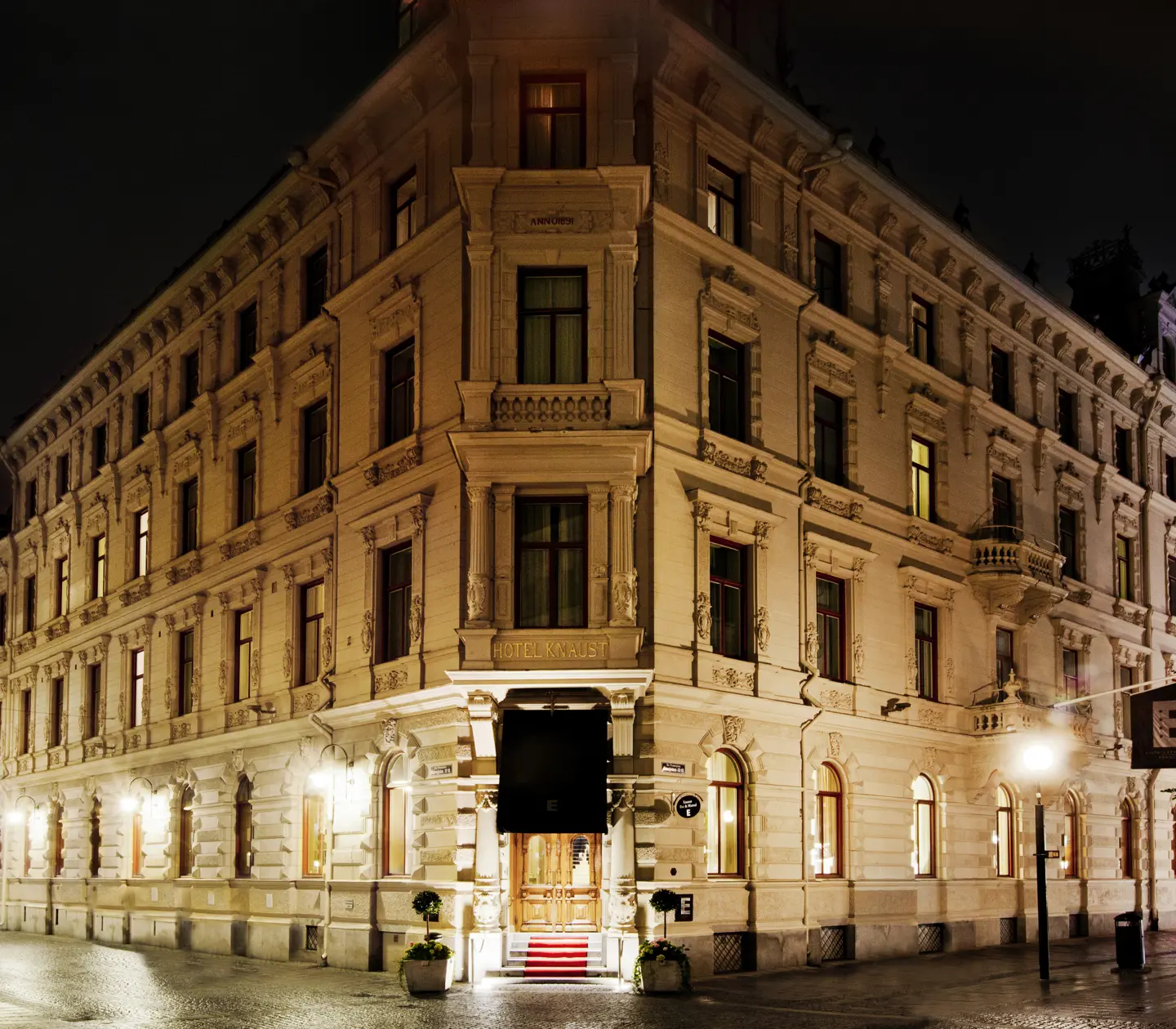 Pampiga vita fasaden av Elite Hotel Knaust i skymning