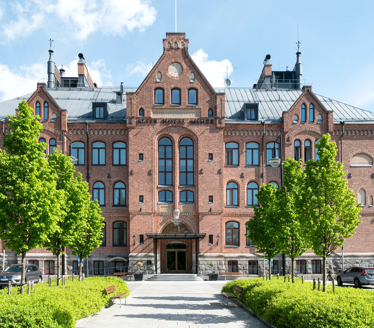 Pampiga tegelfasaden av Elite Hotel Mimer med träd framför