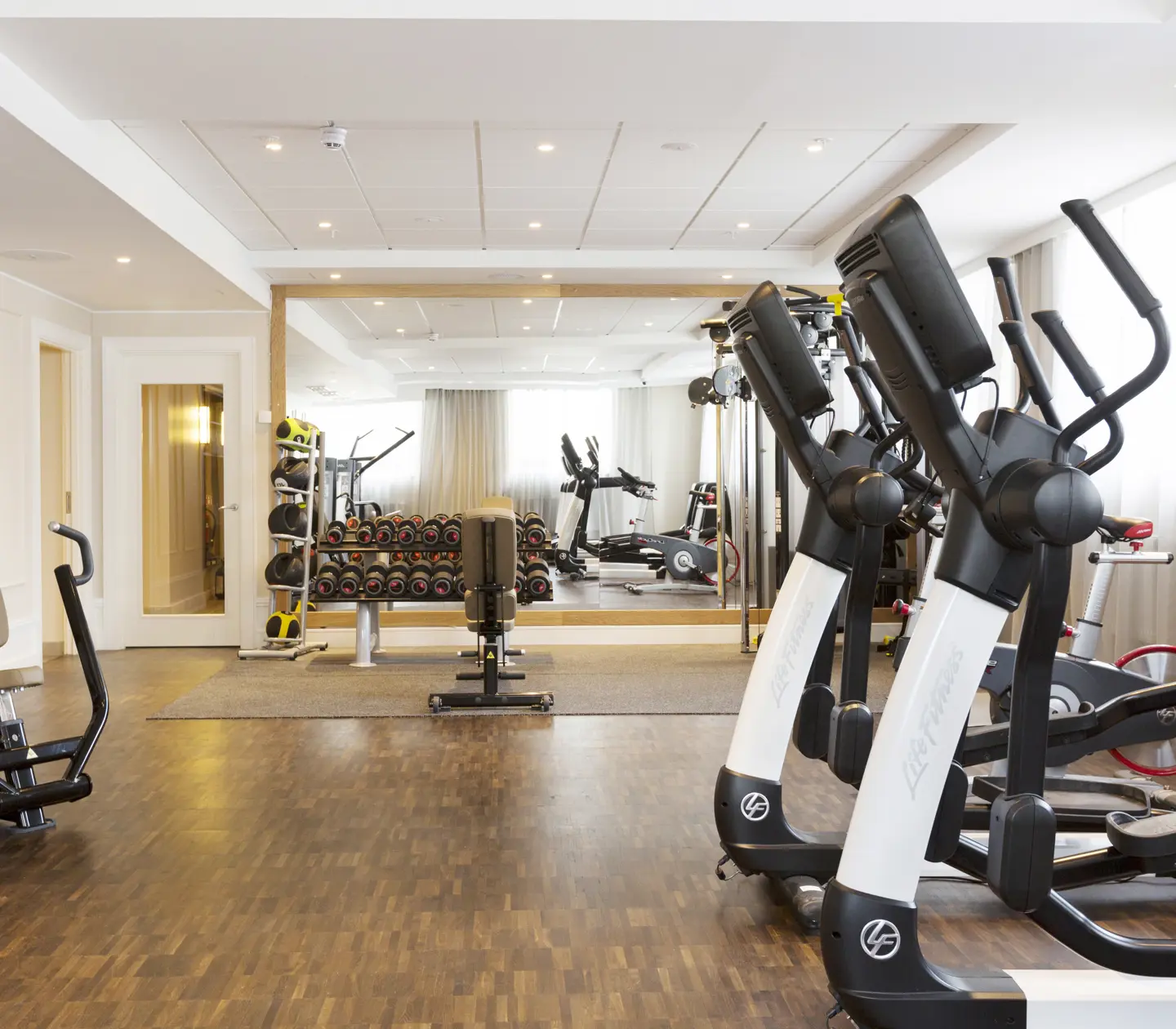 Gymmiljö med träningsmaskiner, hantlar och stor spegel