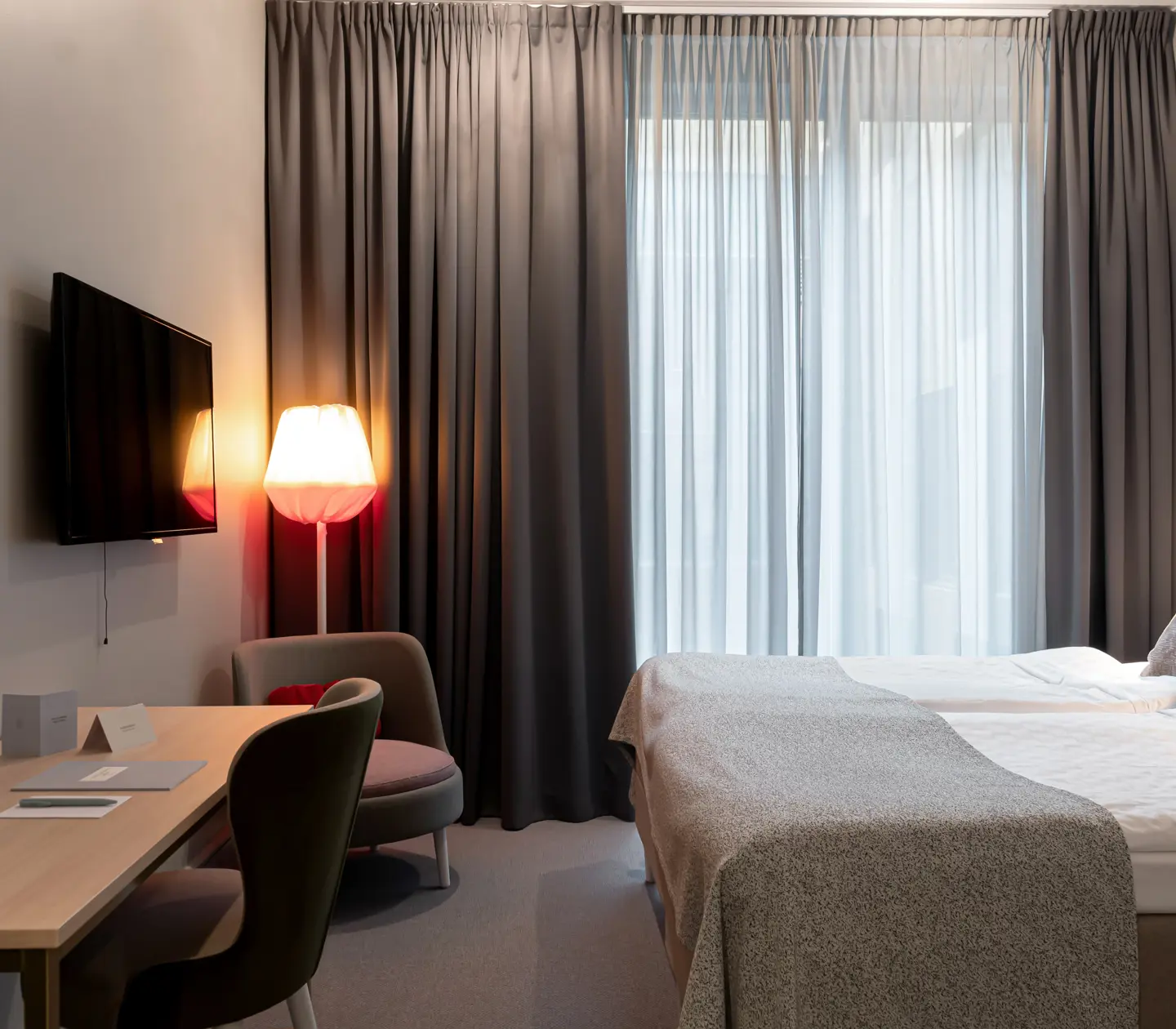 Ljust hotellrum med säng, skrivbord och tv