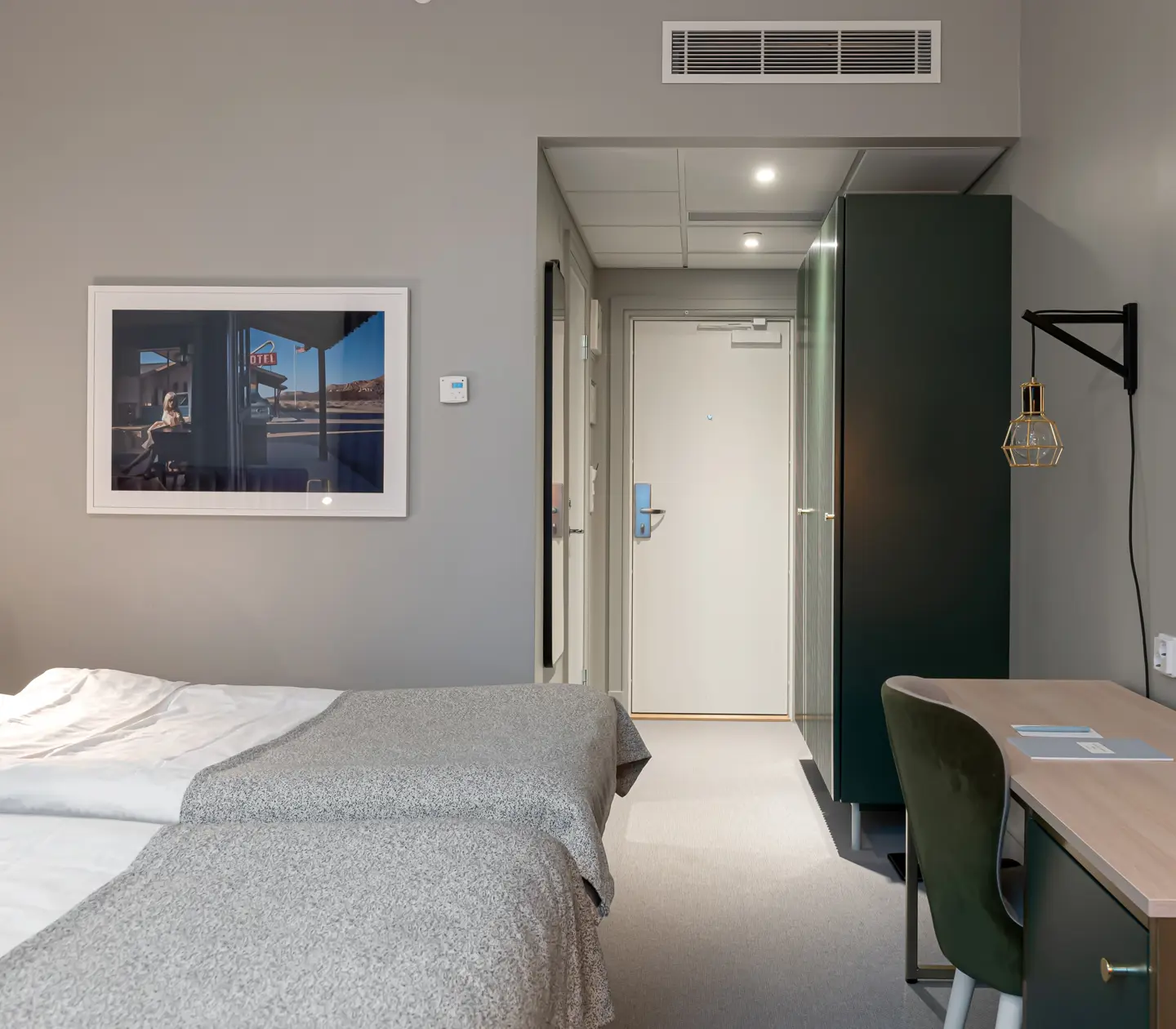 Ljust hotellrum med säng, skrivbord och garderob