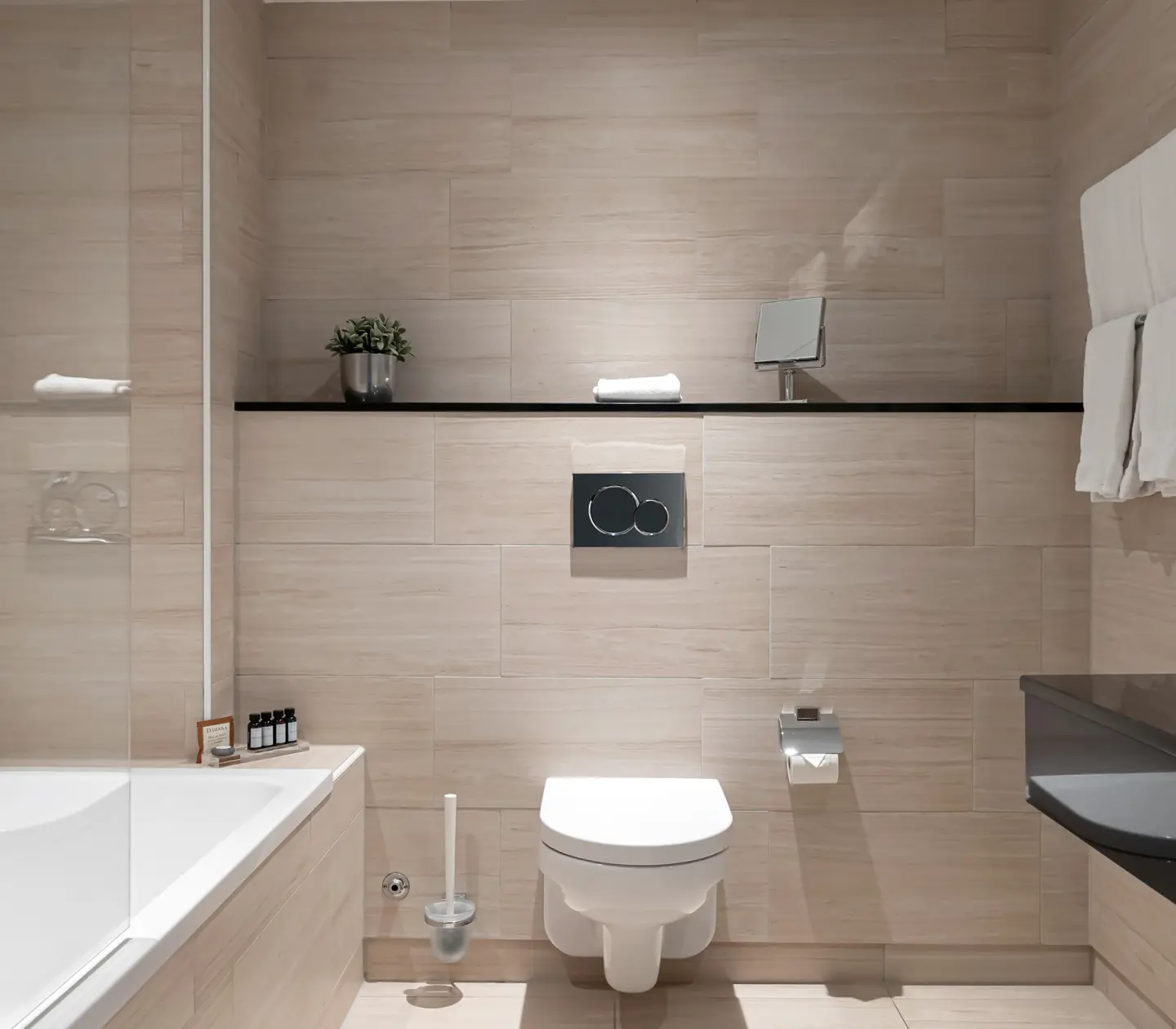 Beige badrum med toalett, badkar och svart handfat