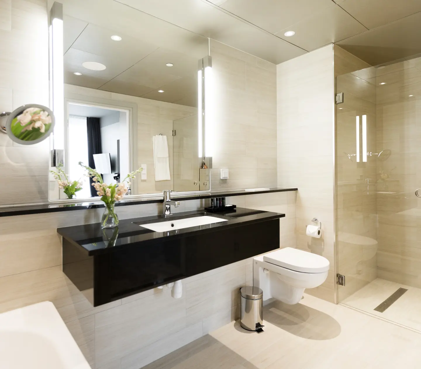 Beige badrum med toalett, dusch och svart handfat