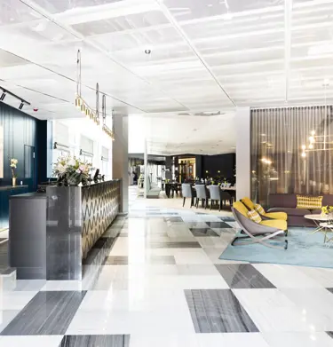 Hotellobby med receptionsdisk, loungemöbler och restaurang i bakgrunden