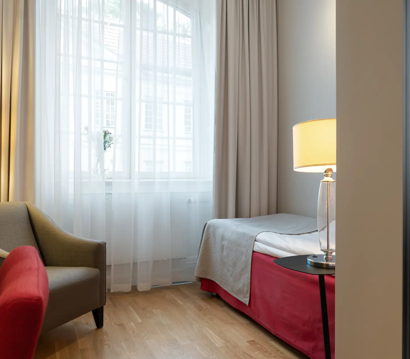 Hotellrum med säng, fåtölj och fönster