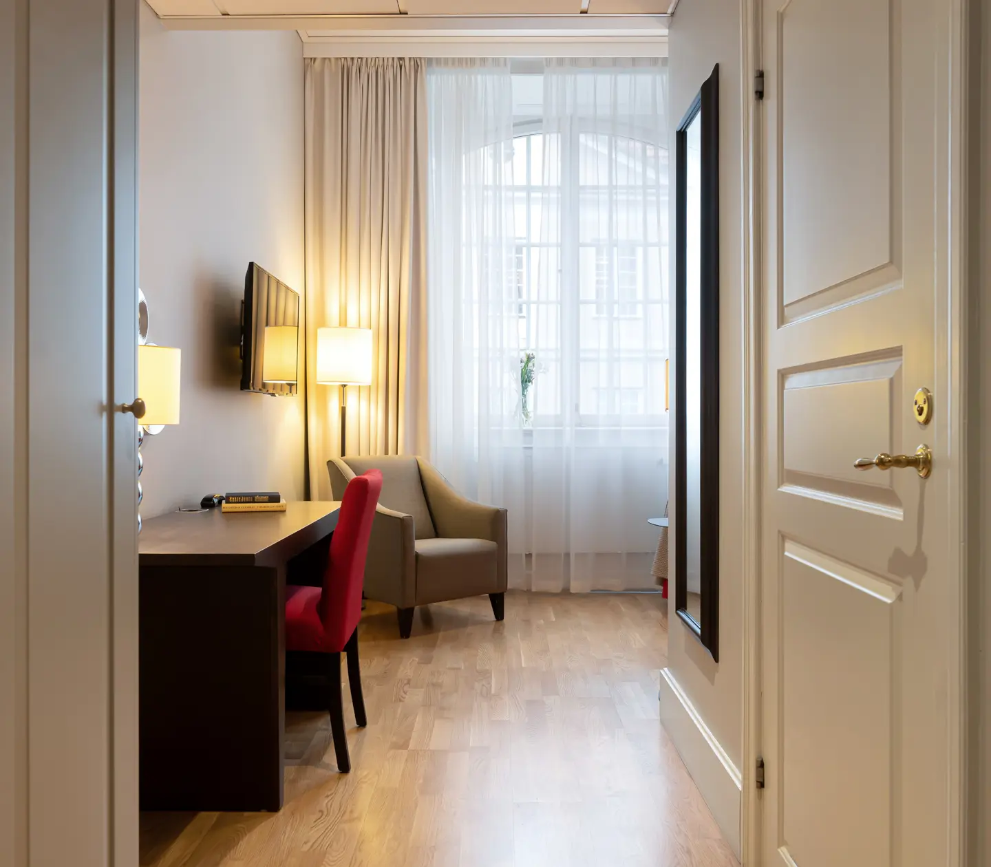Hotellrum med fönster, skrivbord och fåtölj