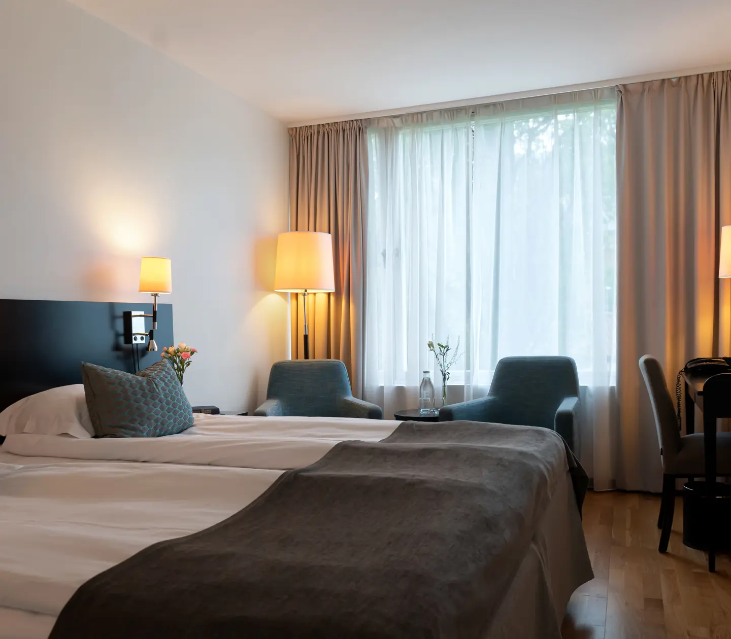 Mysigt hotellrum med säng, fåtöljer och skrivbord