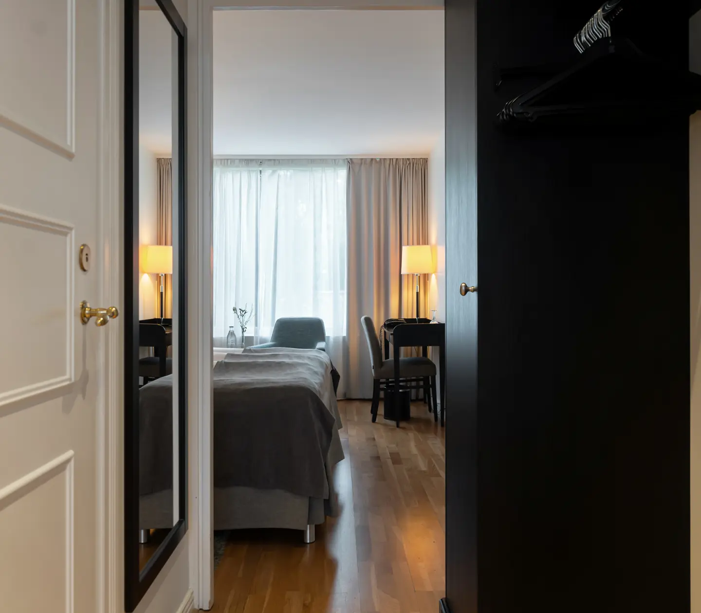Mysigt hotellrum med skrivbord, spegel och garderob