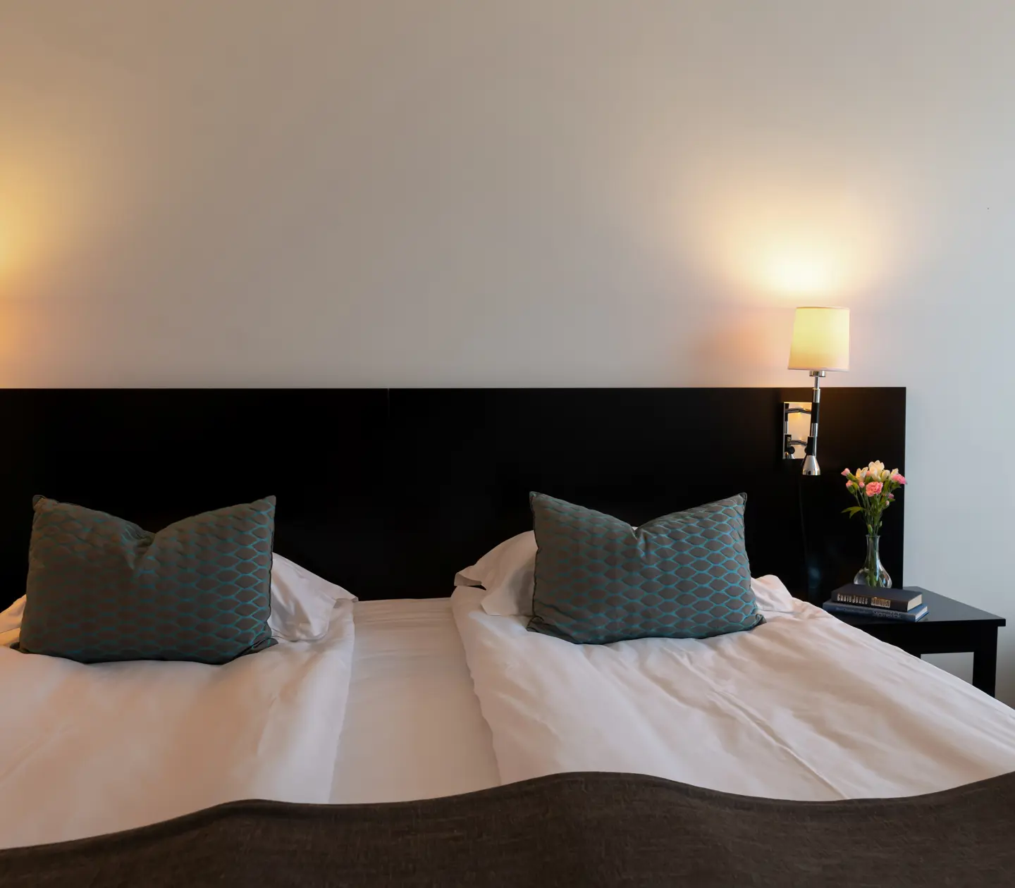 Mysigt hotellrum med säng, svart huvudgavel och sänglampa