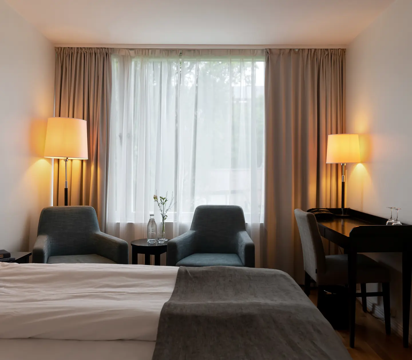 Mysigt hotellrum med säng, fåtöljer och skrivbord