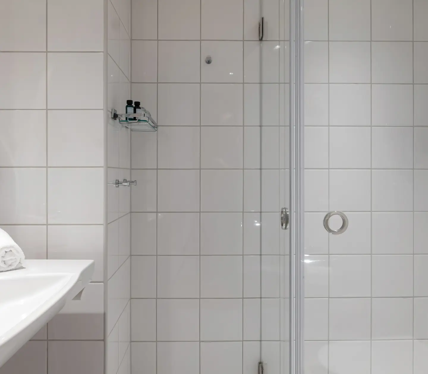 Ljust badrum med handdukar, handfat och dusch