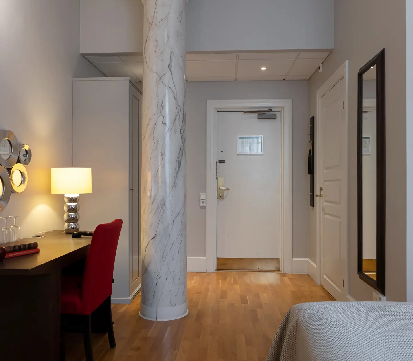 Hotellrum med pelare i marmor, skrivbord och spegel