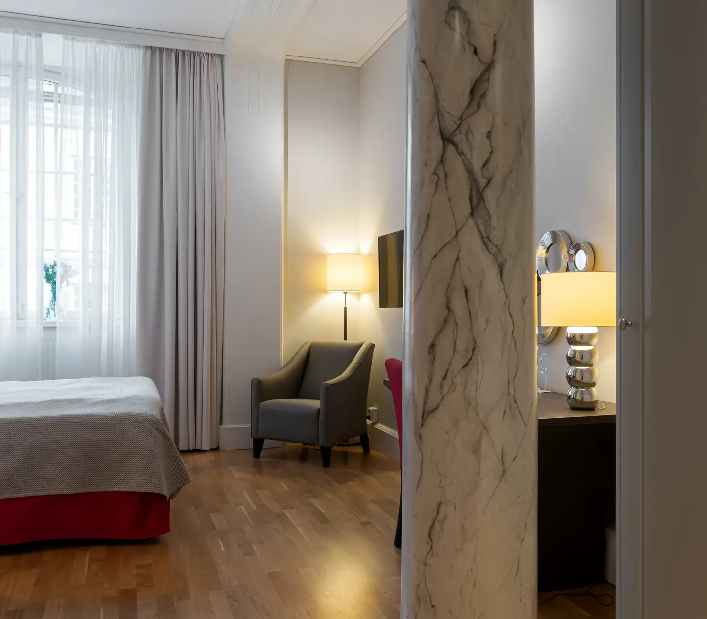 Hotellrum med pelare i marmor, fönster och fåtölj