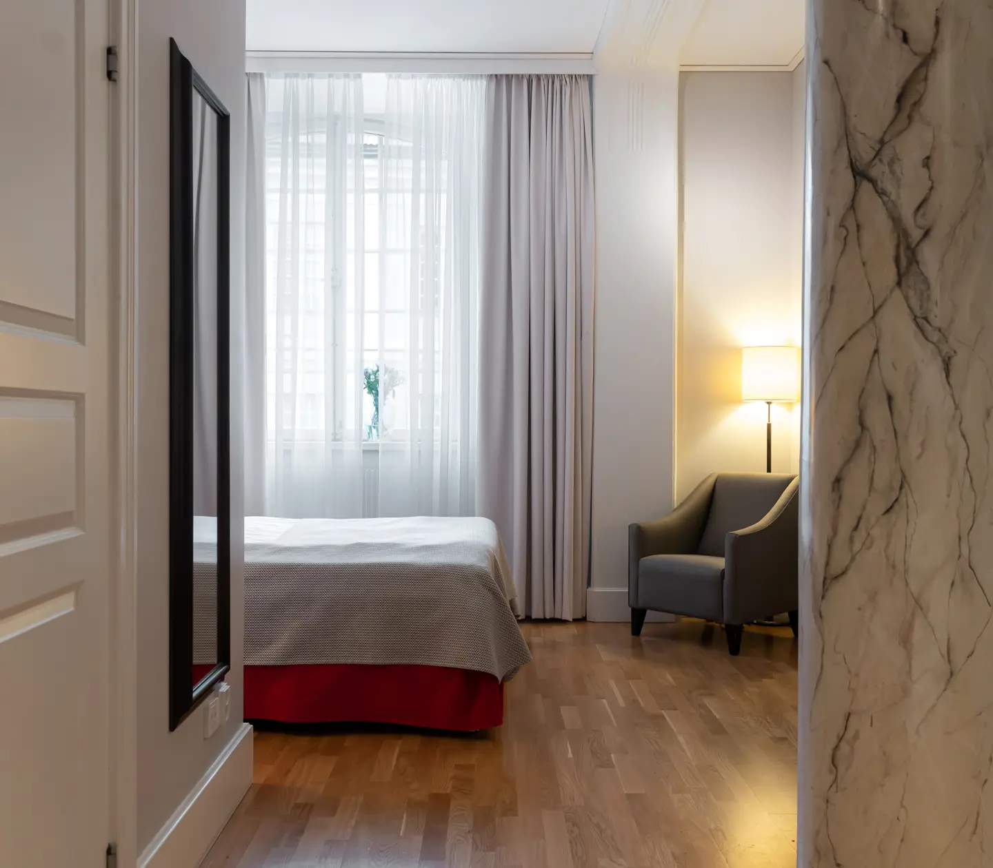 Hotellrum med pelare i marmor, fönster och fåtölj