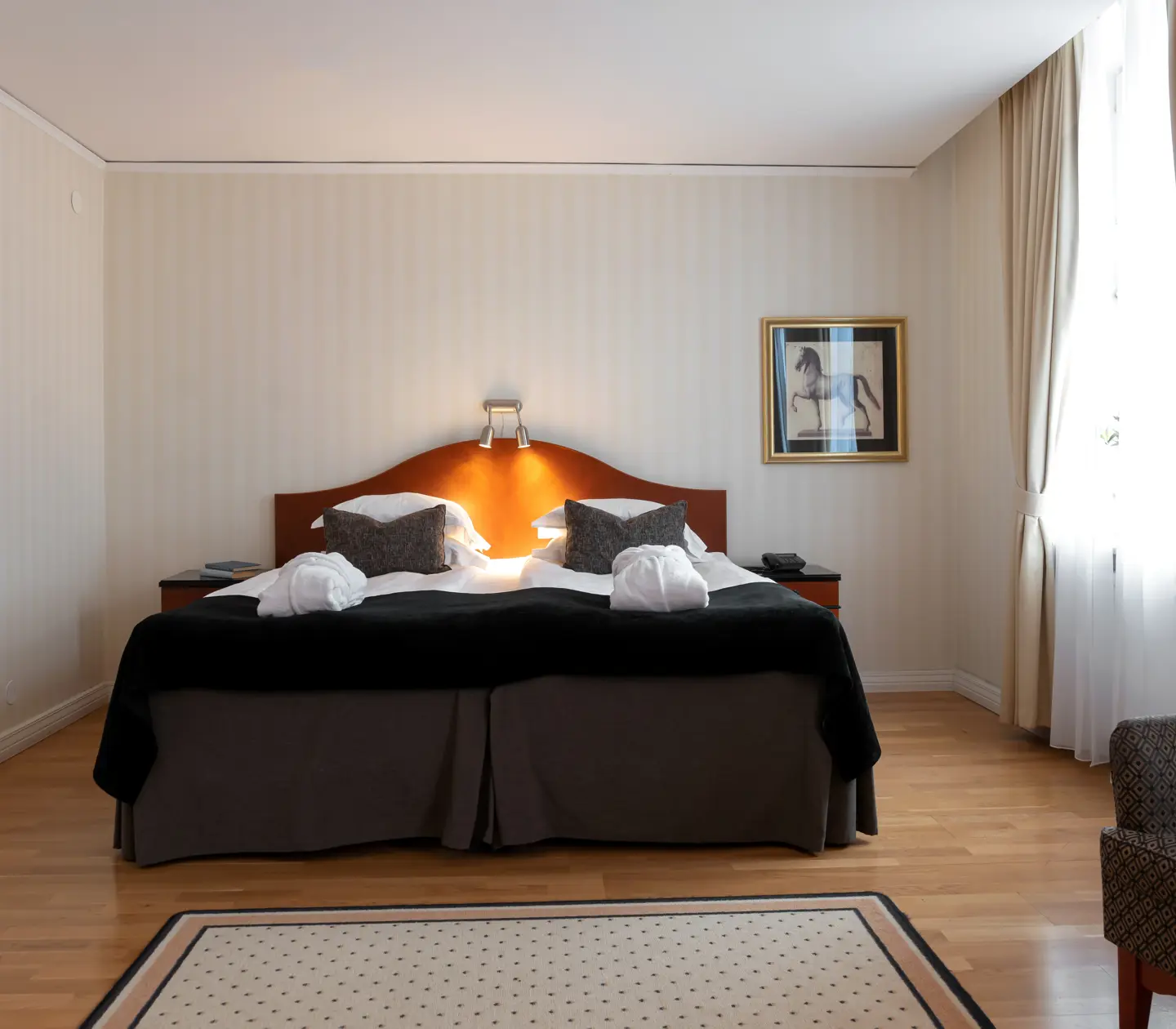 Mysigt hotellrum med morgonrock på säng, fåtölj och fönster