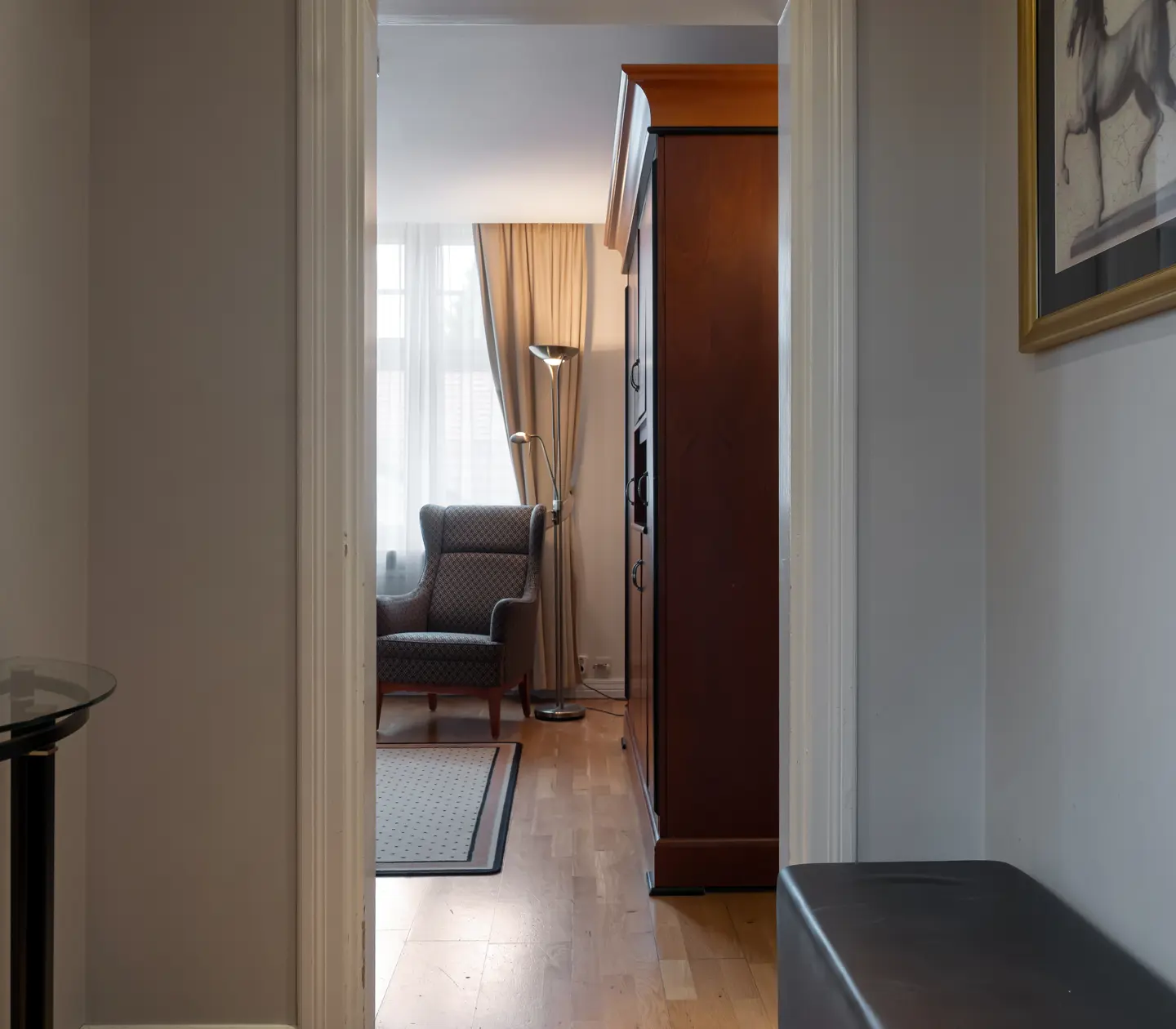 Mysigt hotellrum med garderob, fåtölj och rund spegel