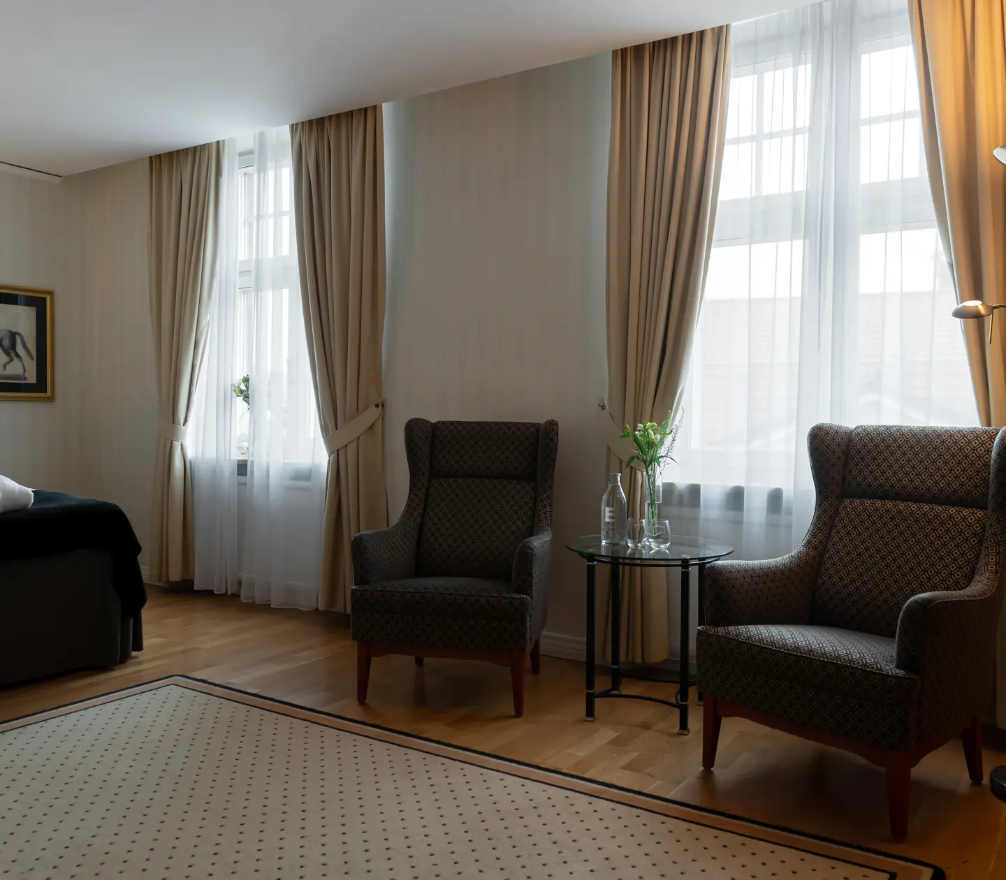 Mysigt hotellrum med morgonrock på säng, fönster och fåtöljer