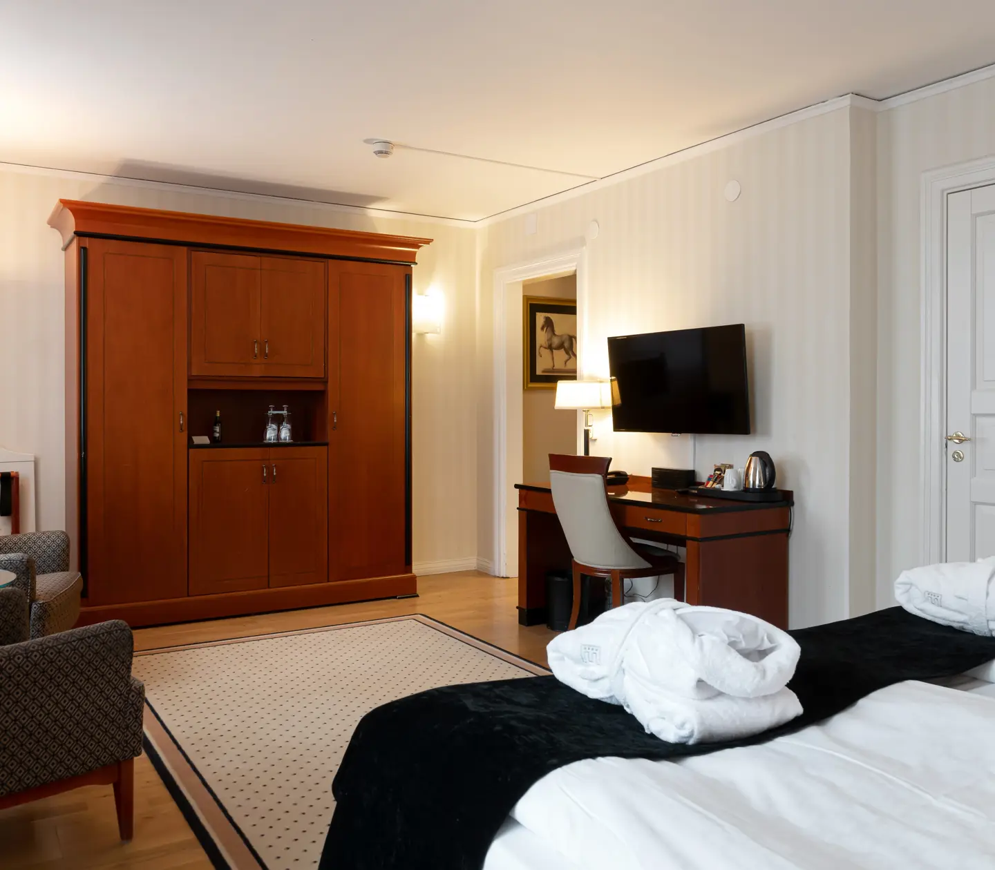 Mysigt hotellrum med morgonrock på säng, garderob och skrivbord