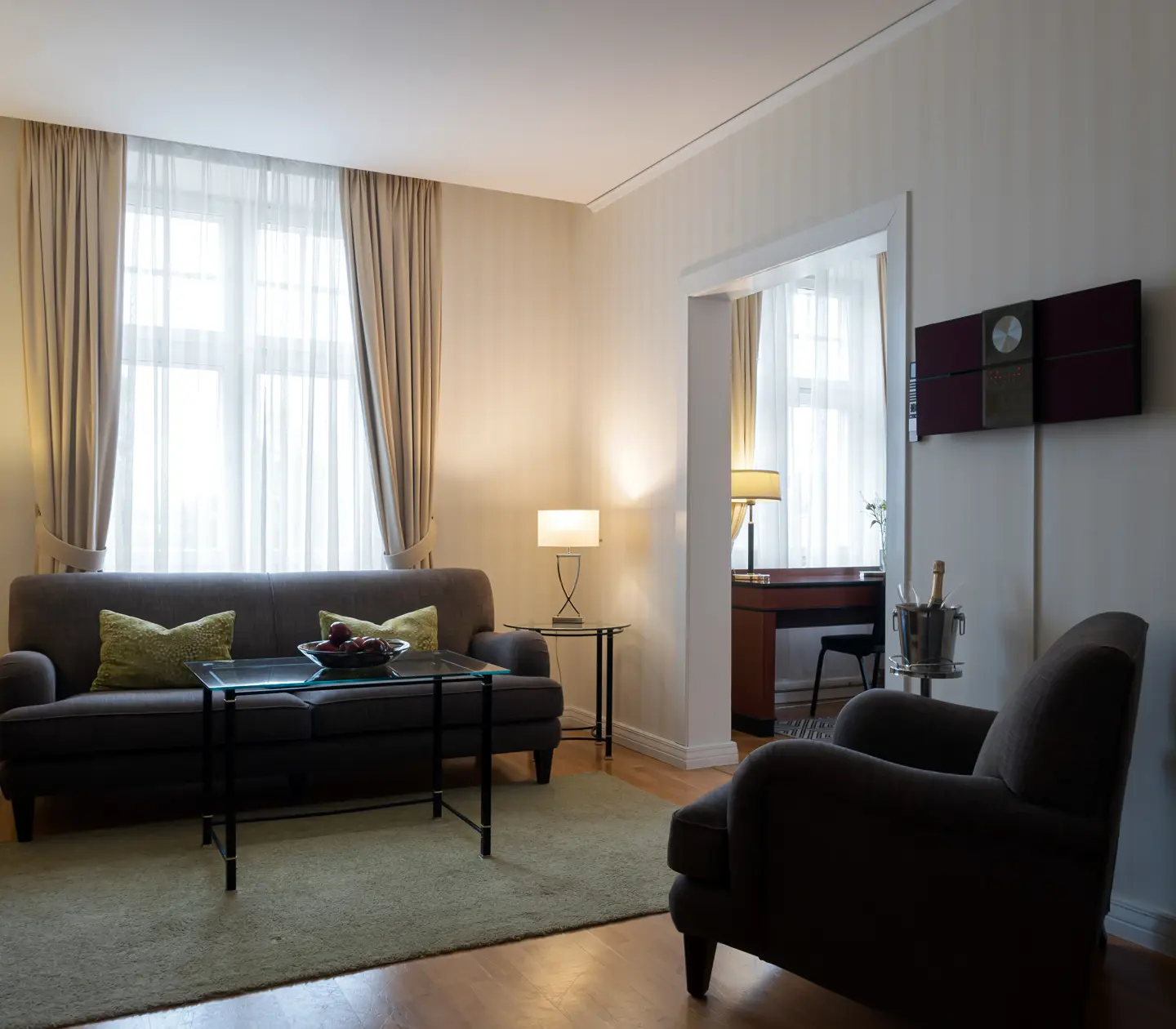 Mysig svit med grå soffgrupp, fönster och skrivbord