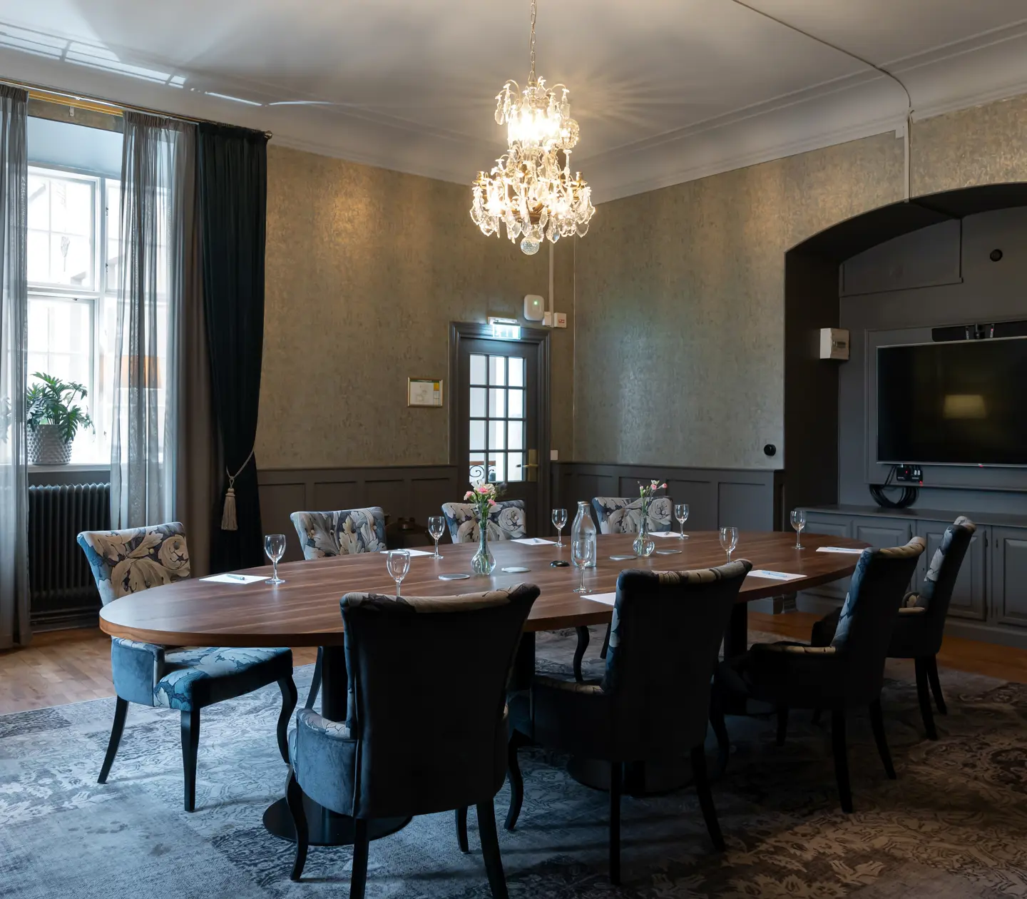Konferensrum med rund bord, tv och kristallkrona