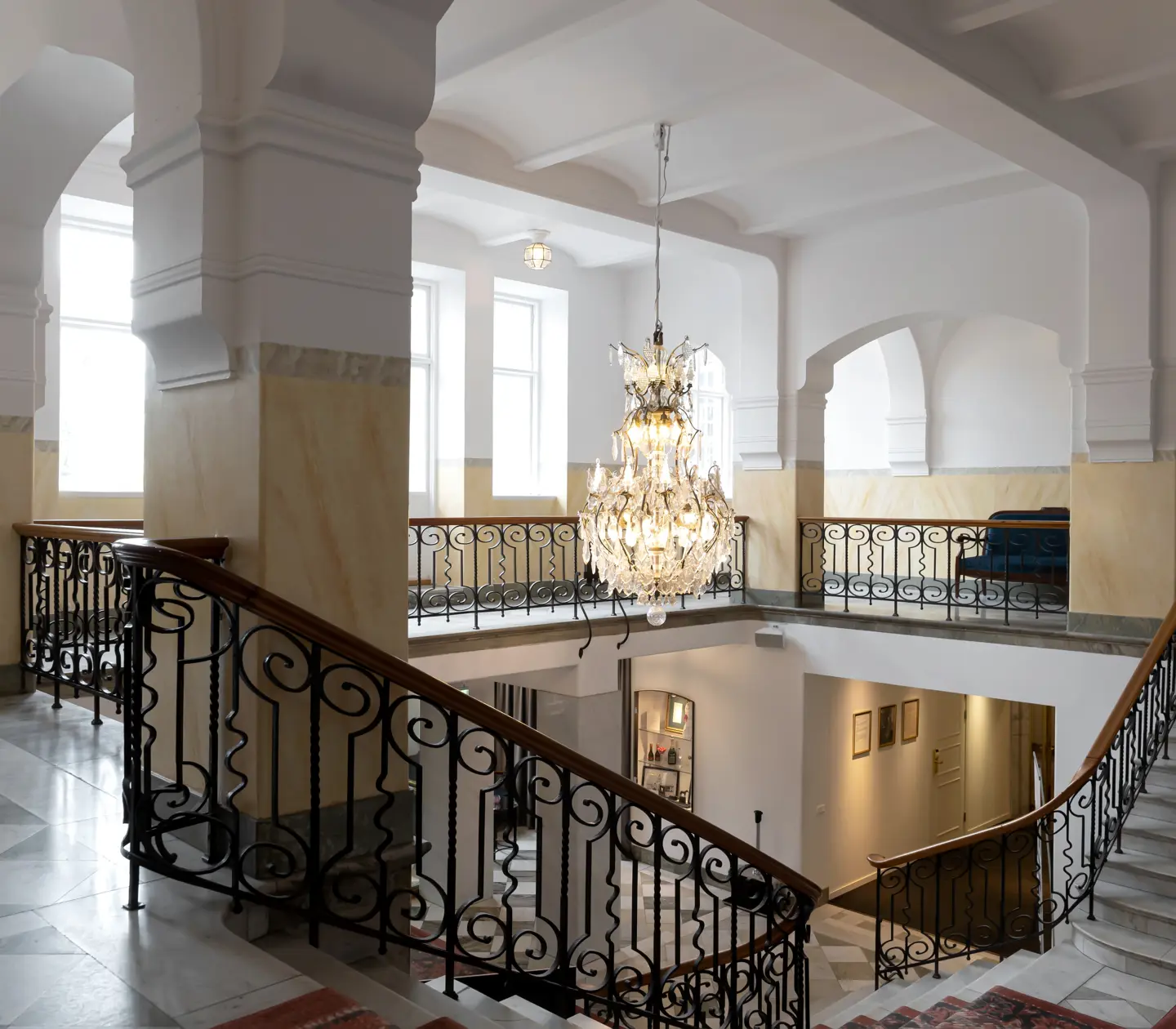 Hotellmiljö med trappor, valv och kristallkrona