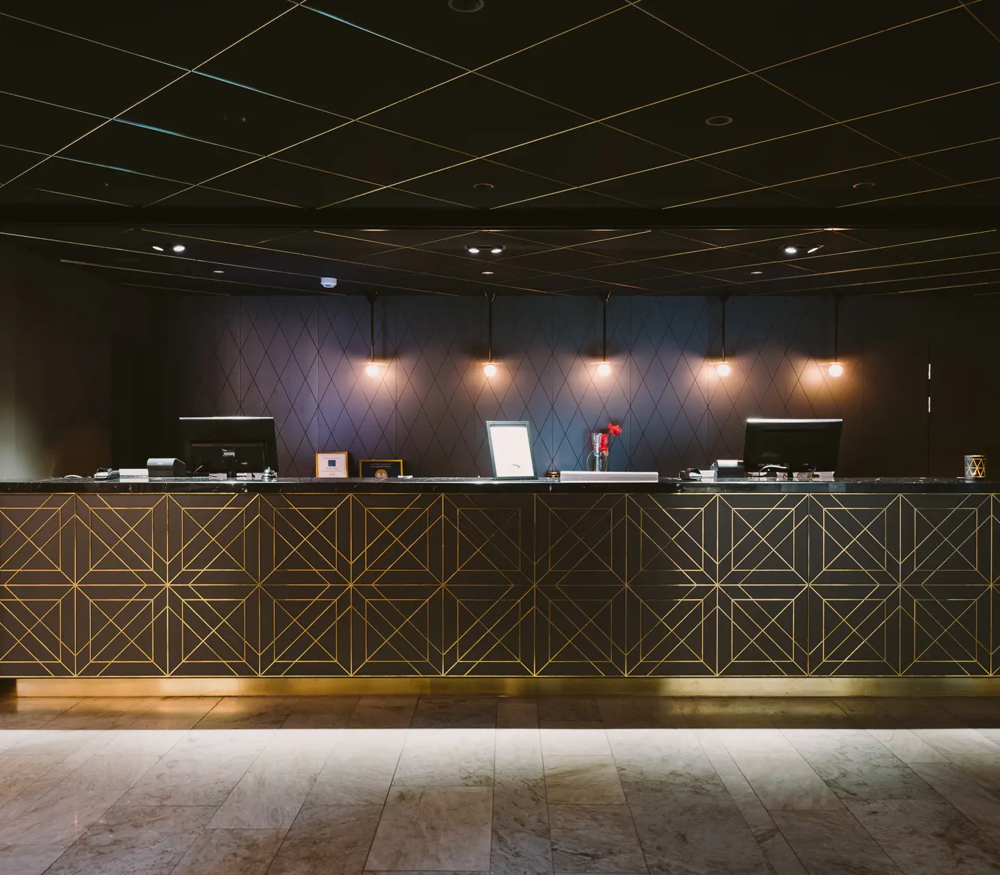 Hotellobby med receptionsdisk med guldiga detaljer och svart tak