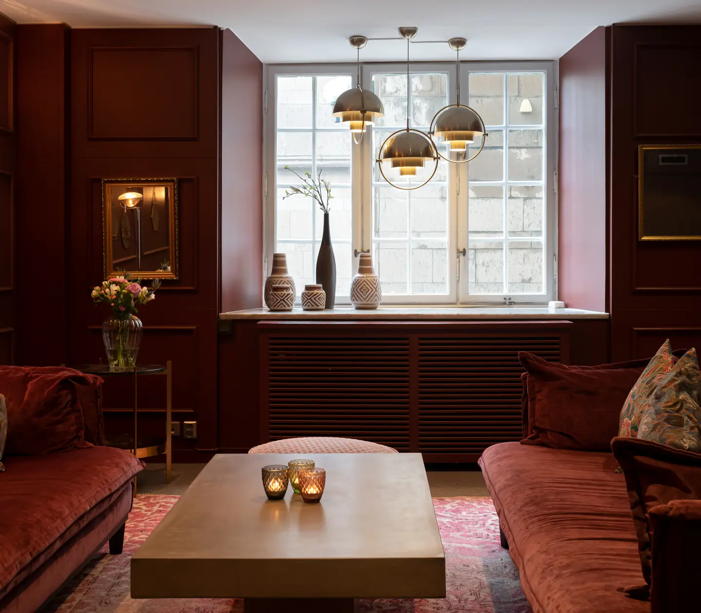 Hotellmiljö med vinröda väggar, röda soffor och fönster