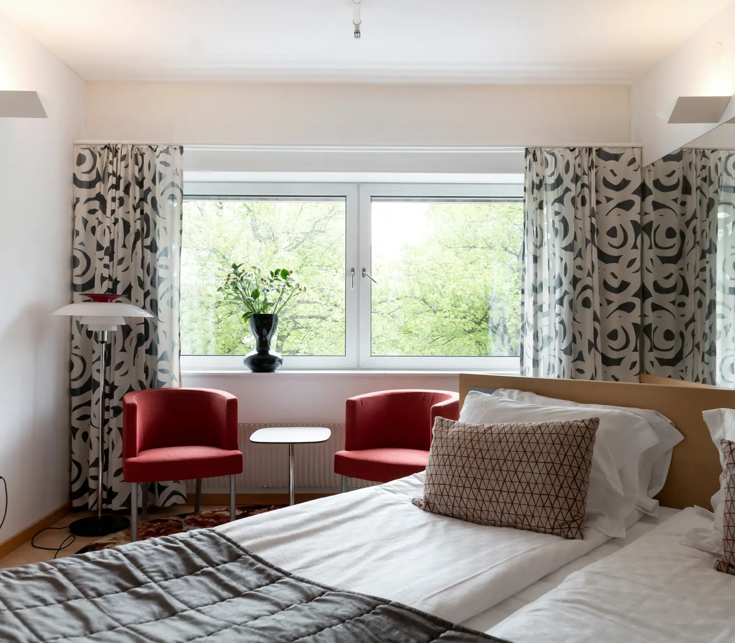 Hotellrum med dubbelsäng, fåtöljer och fönster