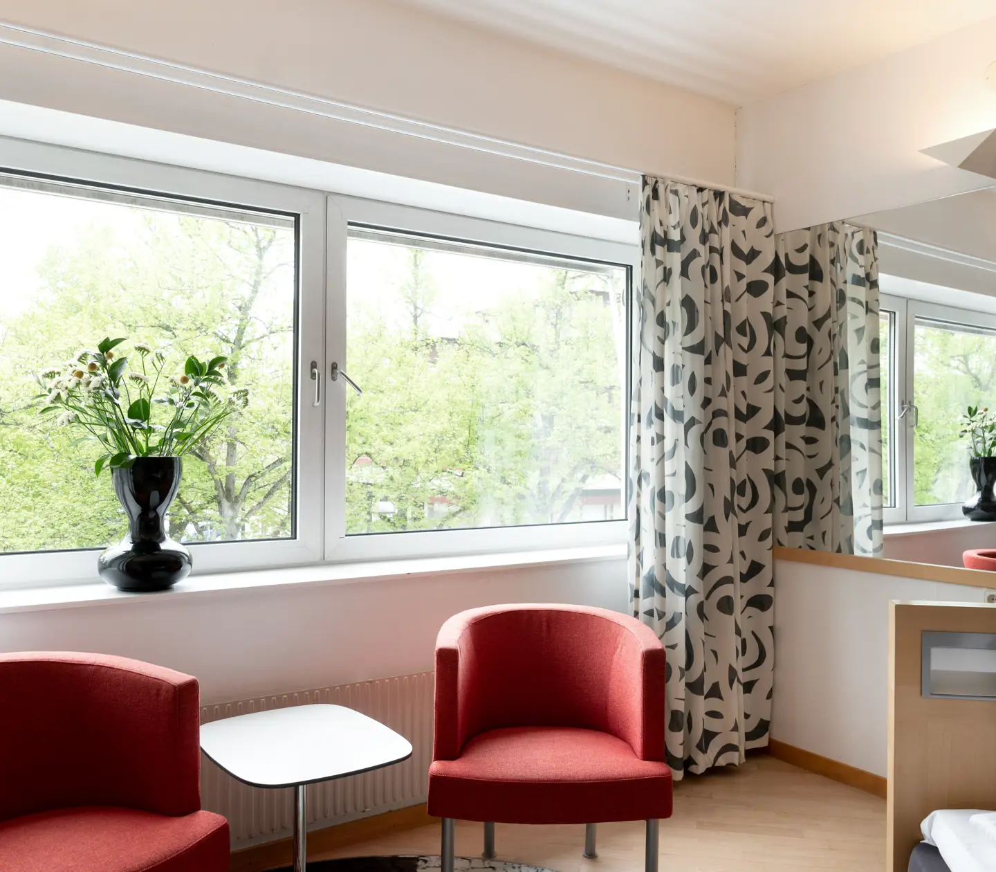 Hotellrum med röda fåtöljer och fönster