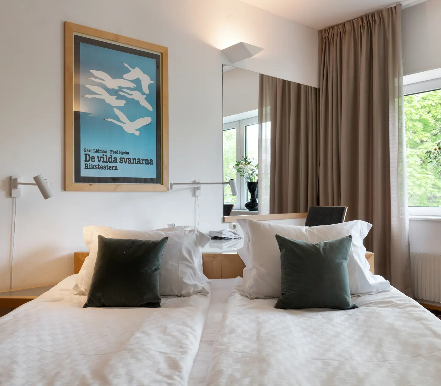 Hotellrum med dubbelsäng, fönster och spegel